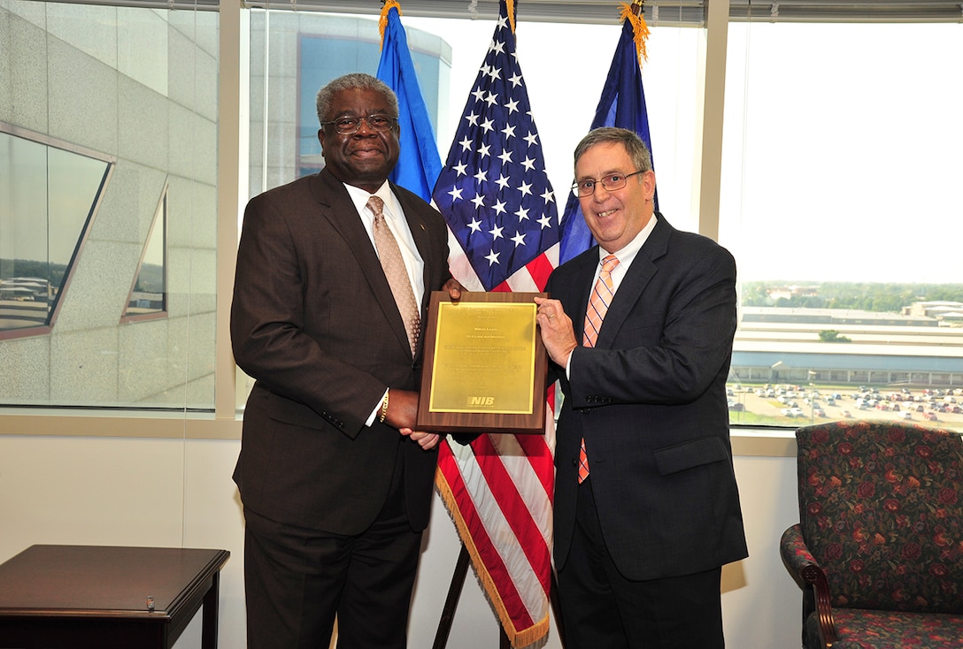 DLA Land and Maritime Acquisition Executive Milton Lewis (left) received a plaque from the National Association for the Employment of People who are Blind and National Industries for the Blind during a ceremony Oct. 6 in the Operations Center at Defense Supply Center Columbus. John Qua, senior vice president of operations for NIB presented the award to Lewis. 