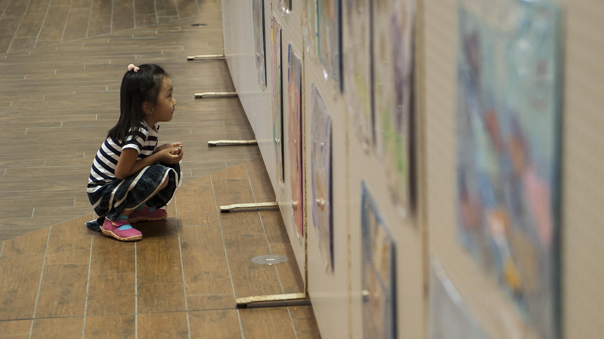 An Okinawan girl looks at pieces of art during the Kadena Special Olympics Art Exhibition at the Rycom Mall Oct. 16, 2016 in Okinawa, Japan. This is the 10th annual KSO Art Exhibition where event organizers display art made by Okinawan children with special needs. (U.S. Air Force photo by Airman 1st Class Corey M. Pettis)
