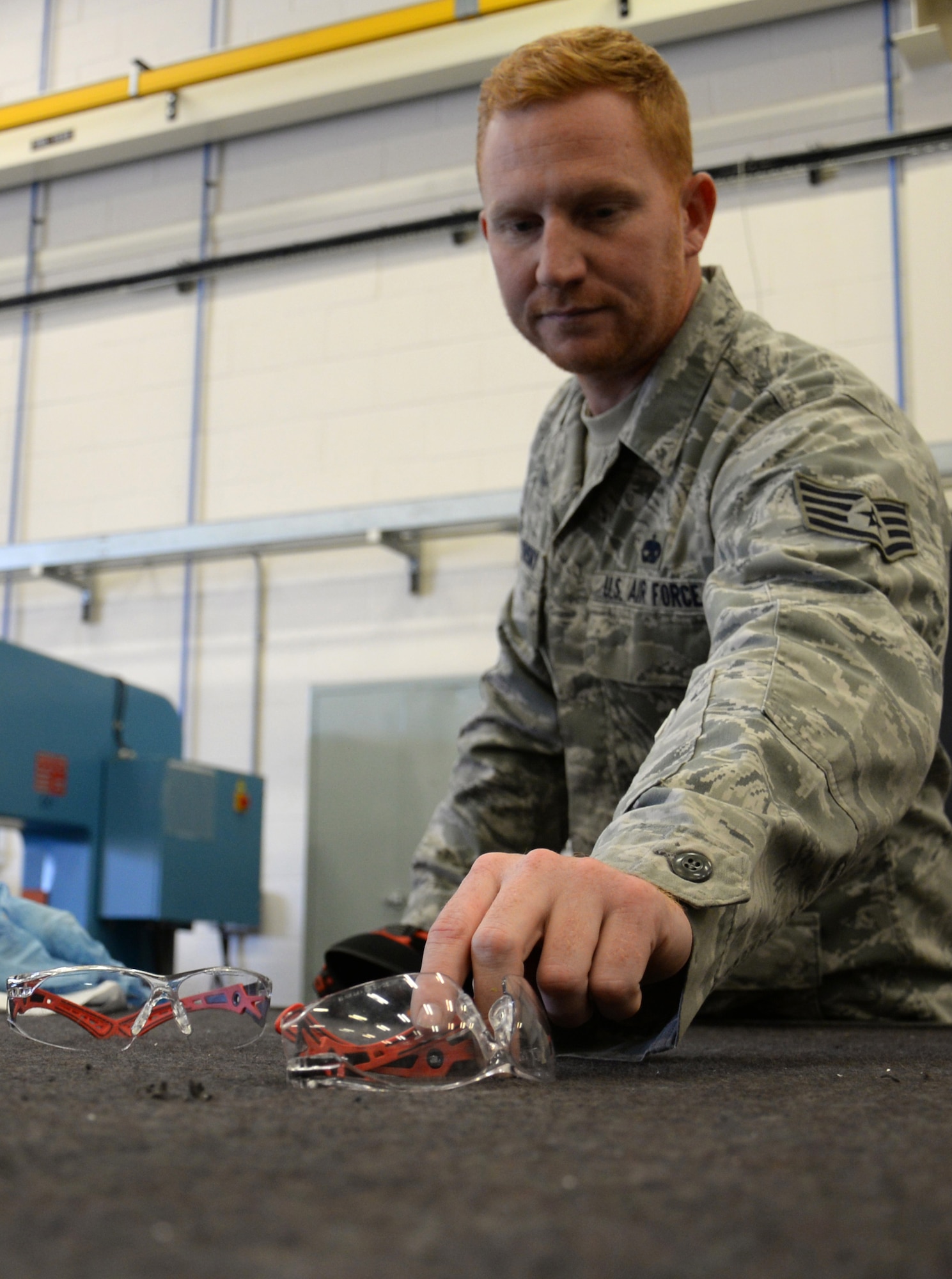 U.S. Air Force Staff Sgt. Zachary Sidlovsky, 100th Maintenance Squadron Aircraft Structural Maintenance craftsman, picks up safety glasses before carrying out his task Oct. 17, 2016, on RAF Mildenhall, England. Safety equipment is vital for maintainers as they carry out their duties. (U.S. Air Force photo by Gina Randall)