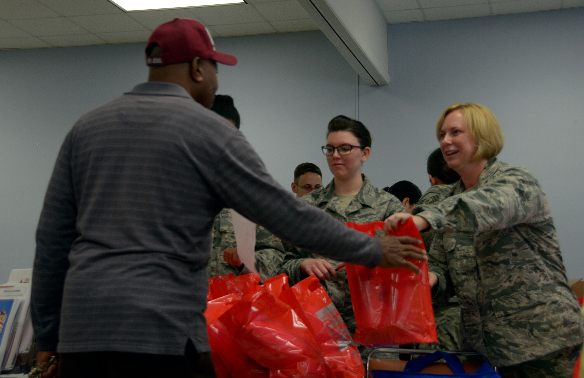 Maj. Melissa Ova, 445th Mission Support Group executive officer, hands a bag filled with necessities to a veteran at the Dayton Veterans Affairs Medical Center Homeless Vets Stand down event in Dayton, Ohio, Sept. 30, 2016. Airmen from the wing volunteered at the annual event that provides a meal, clothing, health screenings, VA and Social Security benefits counseling, and referrals to a variety of other necessary services, such as: housing, employment, substance abuse and mental health treatment services to more than 300 veterans. (U.S. Air Force photo/Staff Sgt. Joel McCullough)