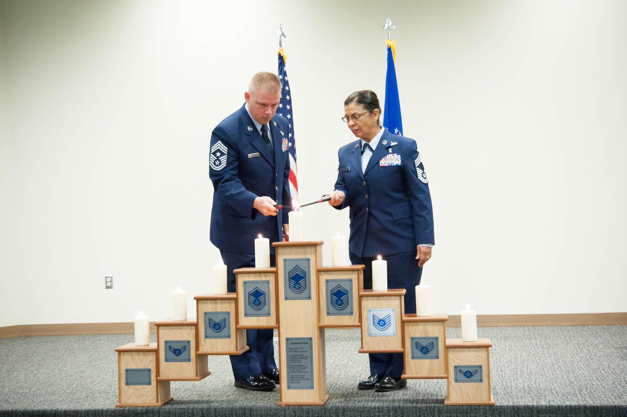 Cheif Master Sgt. Chris Barnby, 403rd Wing command chief and Chief Master Sgt. Josephine Keller, 403rd Aeromedical Staging Squadron superintendent light the candle that represents reaching the rank of chief master sergent during the 403rd Wing's noncomissioned and senior noncomissioned officer induction ceremony at the Roberts Consolidated Aircraft Maintenance facility Oct. 16. (U.S. Air Force photo/Senior Airman Heather Heiney)