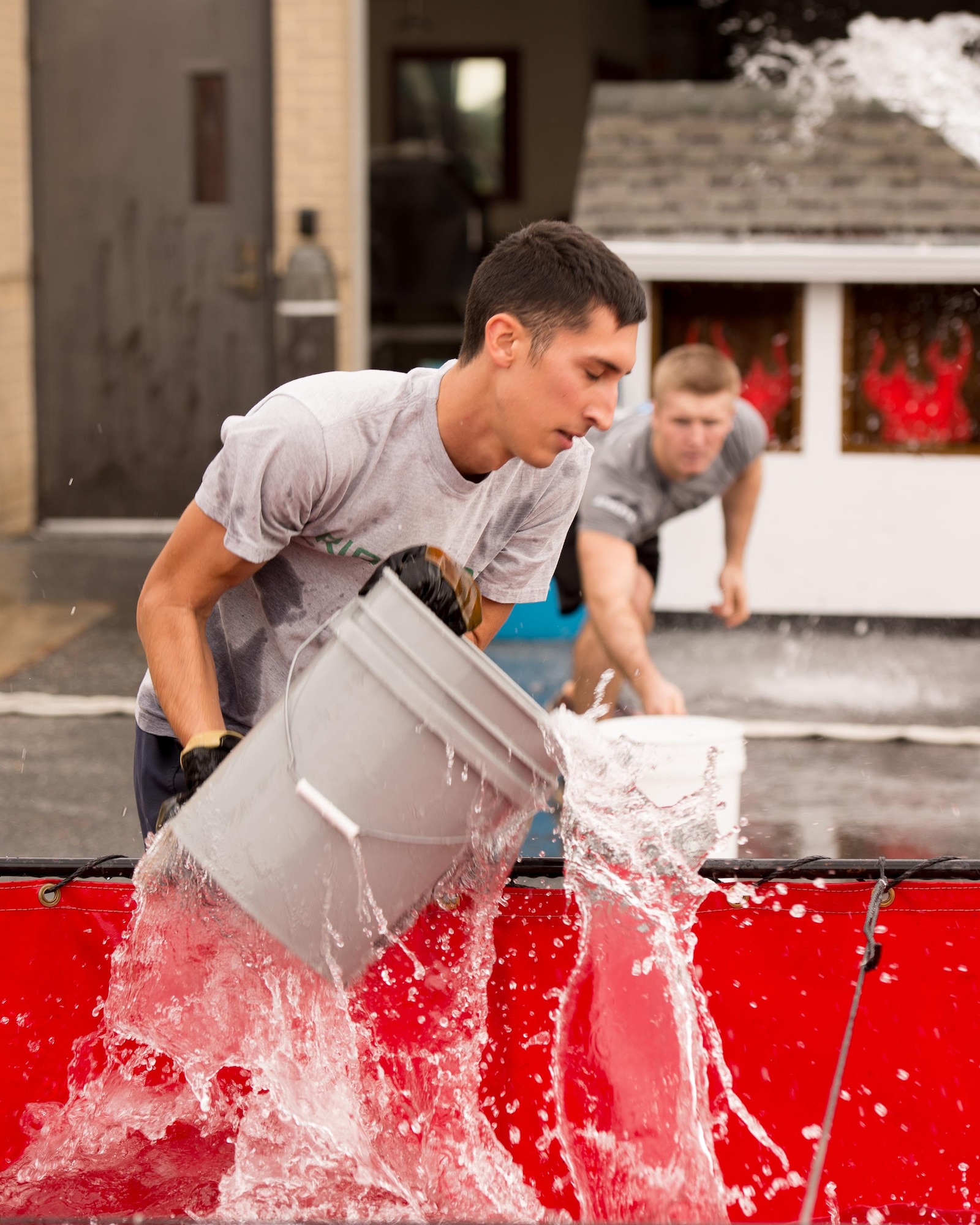 Airmen with 436th Maintenance Squadron Isochronal Inspection team fill buckets of water during the 2016 Fire Muster competition Oct. 13, 2016, on Dover Air Force Base, Del. Two team members filled the buckets while the other two poured them onto a mock house fire. (U.S. Air Force photo by Mauricio Campino)