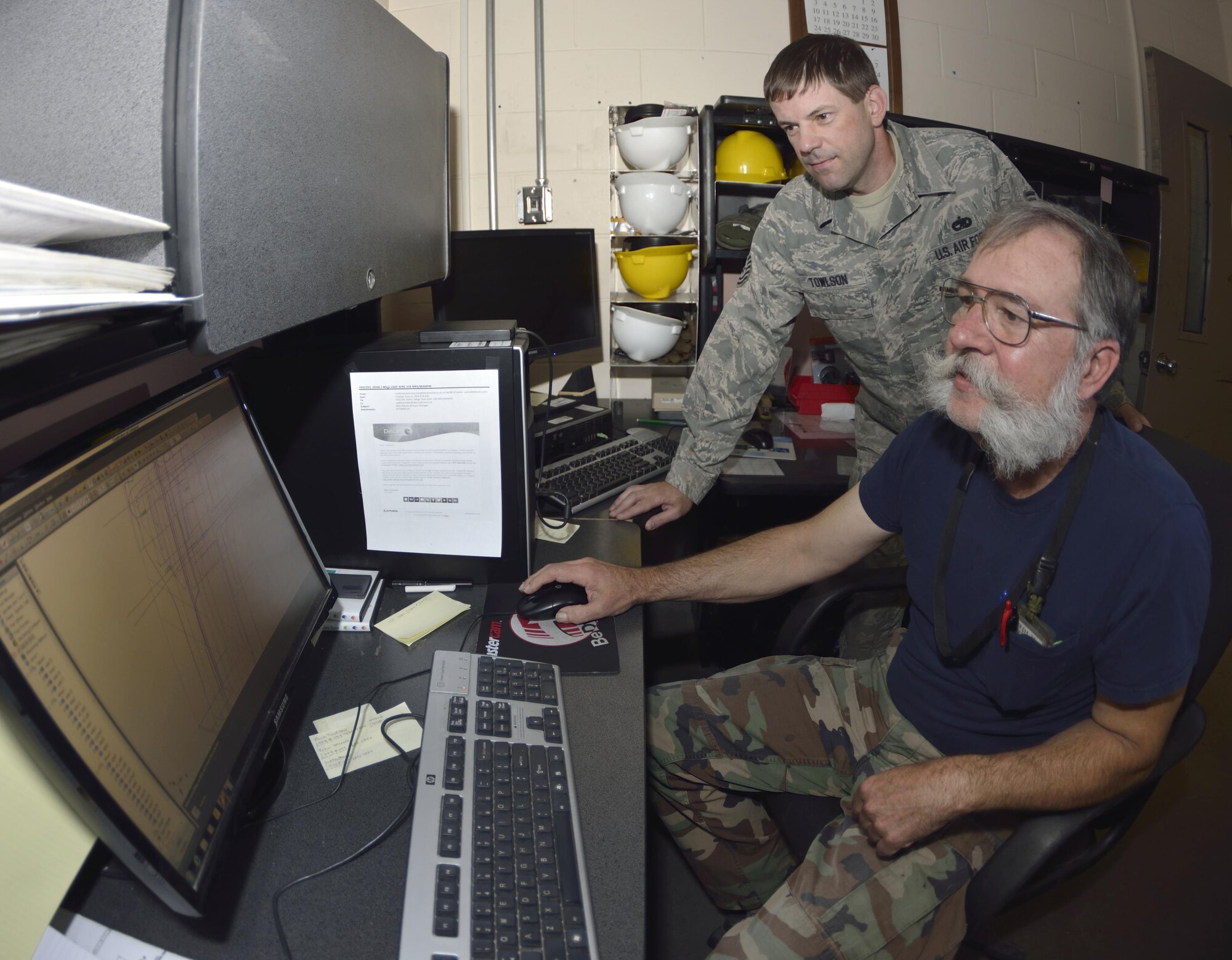 Tech. Sgt. Richard Towlson and Mr. Gary Surozenski check thousands of lines of code on their CAD computer that is used to give instructions to the milling machine. This computer and data put into the CAD program is the first step in building a new part for the C-5.