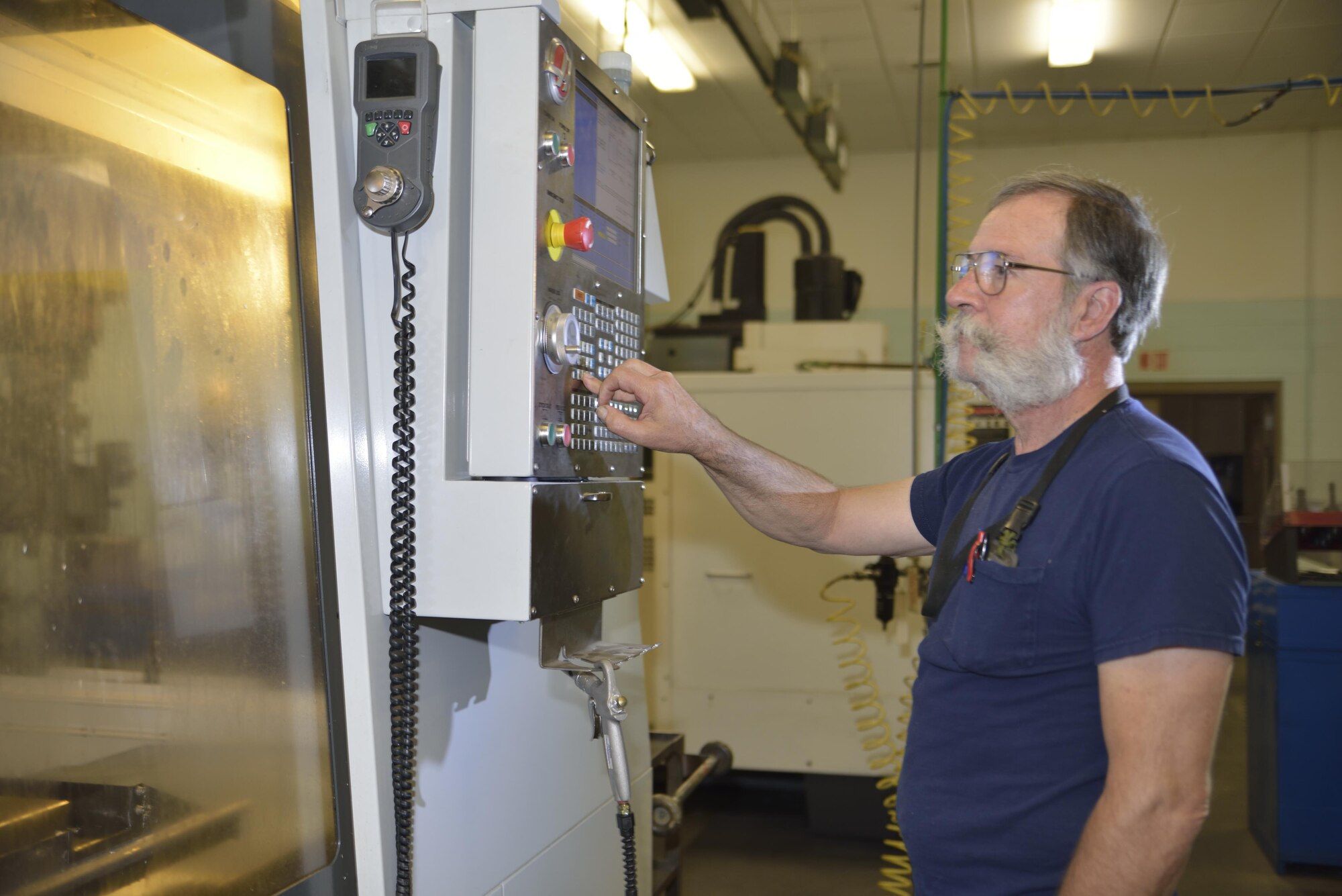 Mr. Gary Surozenski, metal technician checks the line by line coding of the converted CAD program file on the milling machine's control panel.