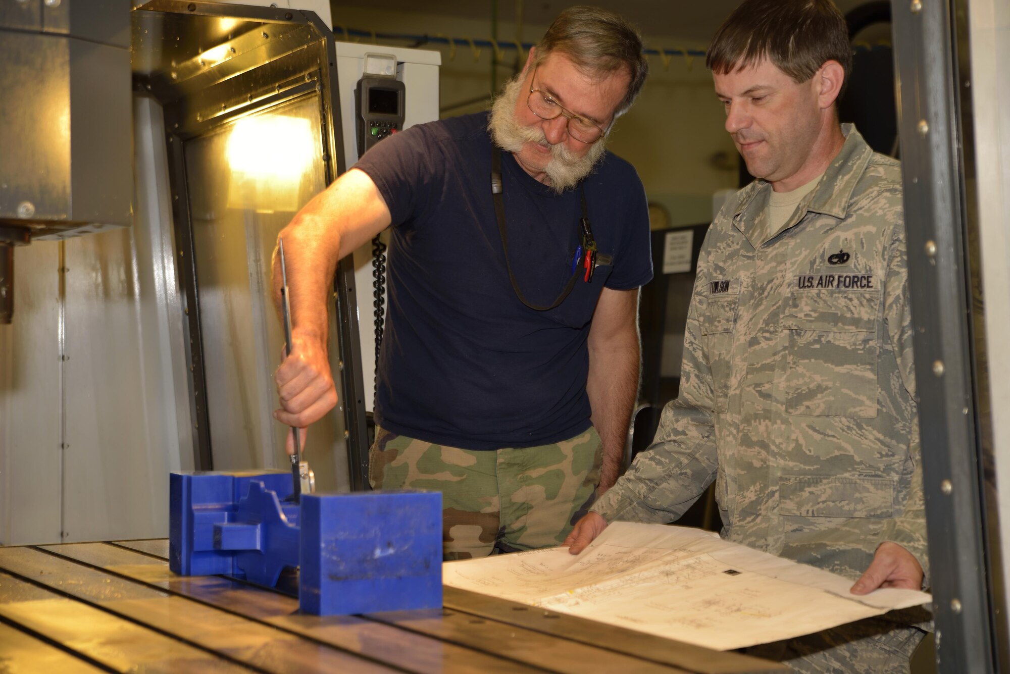Mr. Gary Surozenski and Tech. Sgt. Richard Towlson check and re-check the measurements with the blue prints. To make sure the milling machine will make the right cuts they first use a wax moch-up.