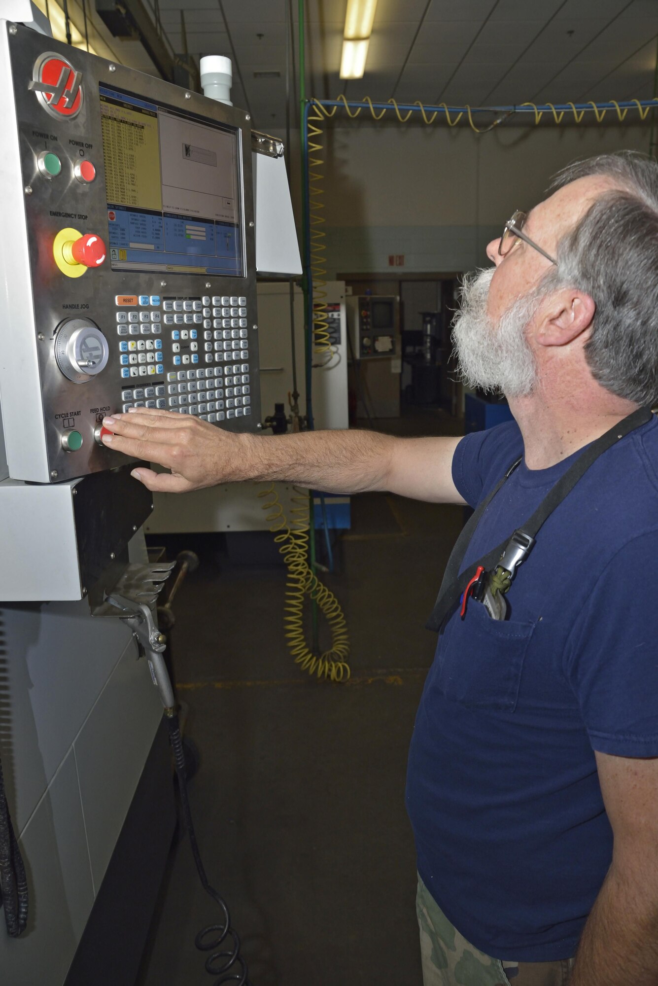 Mr. Gary Surozenski, metal technician checks the line by line coding of the converted CAD program file on the milling machine's control panel.