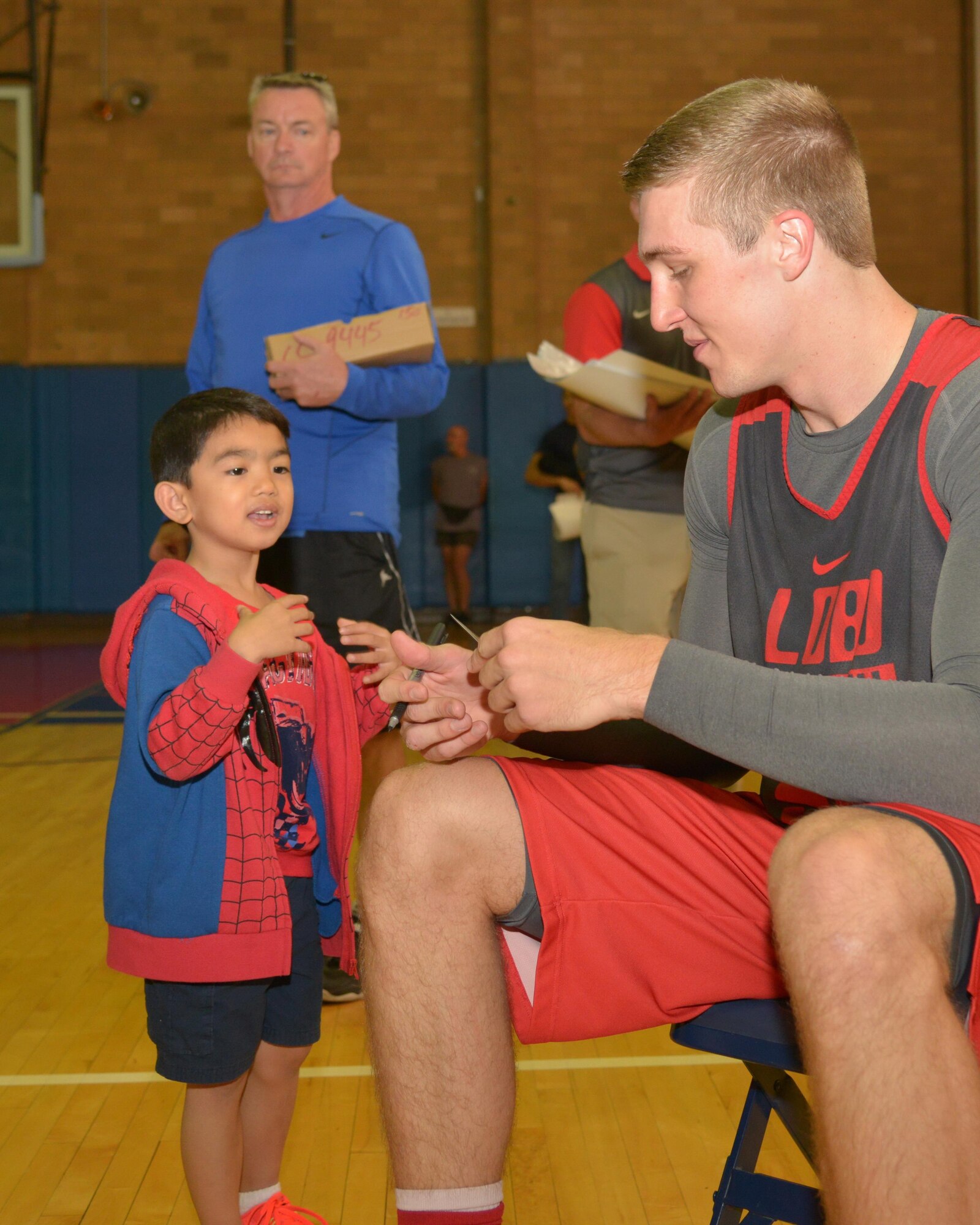 UNM Lobos men's basketball player Connor MacDougall signs an autograph for a young fan following a scrimmage at the Kirtland East Fitness Center Oct. 15. About 100 fans watched the scrimmage, which was scheduled on base to allow the team to show appreciation to military members. 