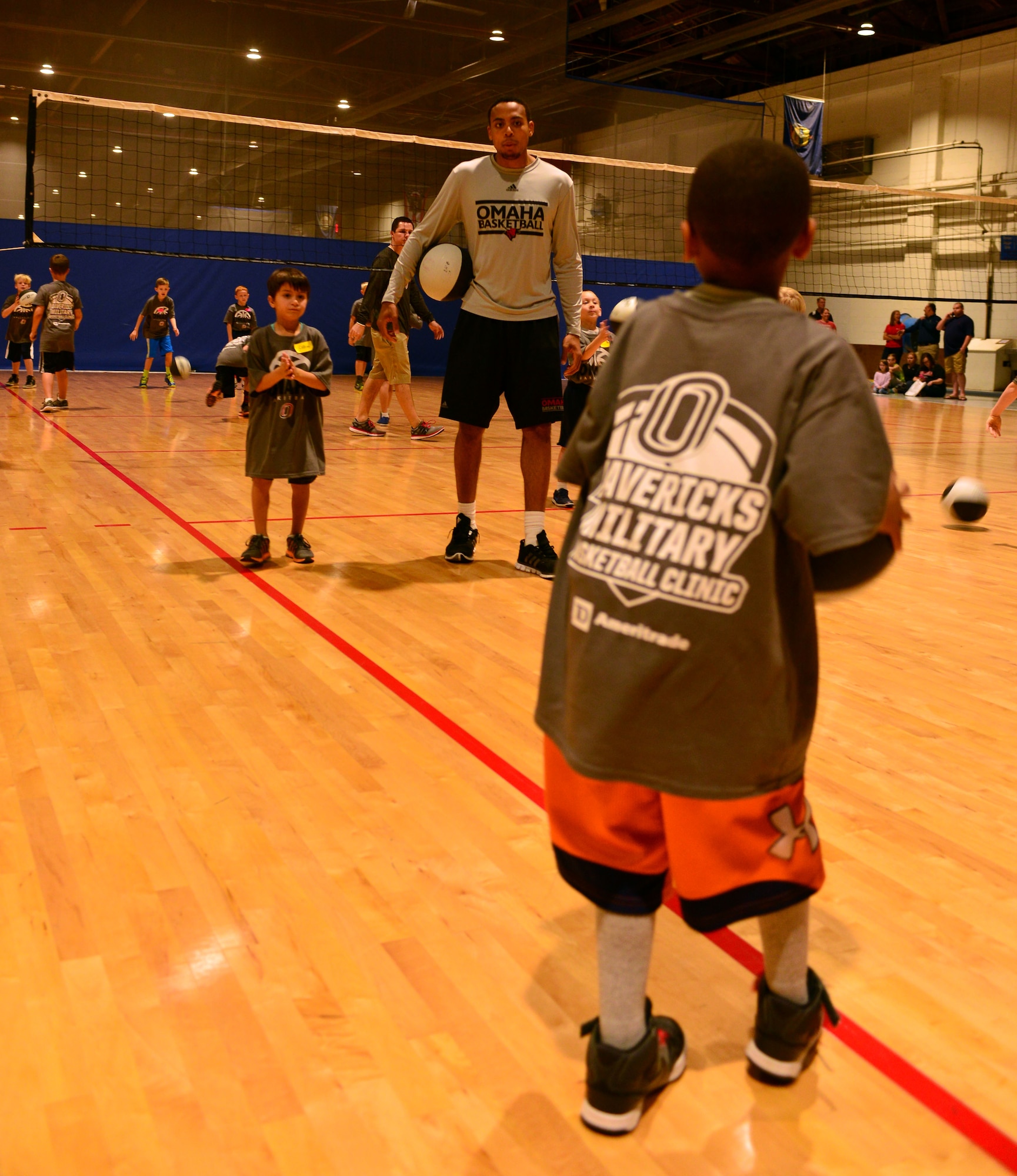 JT Gibson, University of Nebraska Omaha freshman, helps Team Offutt children refine their passing skills Oct. 15, 2016 at the Offutt Field House.  The UNO Mavericks’ men’s and women’s basketball teams provided a free basketball clinic to more than 100 military-affiliated children. Nebraska Governor Pete Ricketts spoke to the campers and passed along thanks from the citizens of Nebraska to the members of Team Offutt.