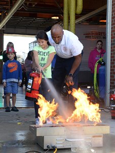 Keith Boyd, Fort Eustis Fire and Emergency Services assistant fire chief, cheers on Victoria, age 10, daughter of U.S. Army Staff Sgt. Terrance Haggard, 2nd Staff and Faculty, U.S. Army Transportation School instructor, as she puts out a fire during Fire Prevention Week at Joint Base Langley-Eustis, Va., Oct. 15, 2016. Children were given the opportunity to extinguish a fire, while supervised by firefighters, to understand how to properly use an extinguisher. (U.S. Air Force photo by Staff Sgt. Teresa  J. Cleveland)