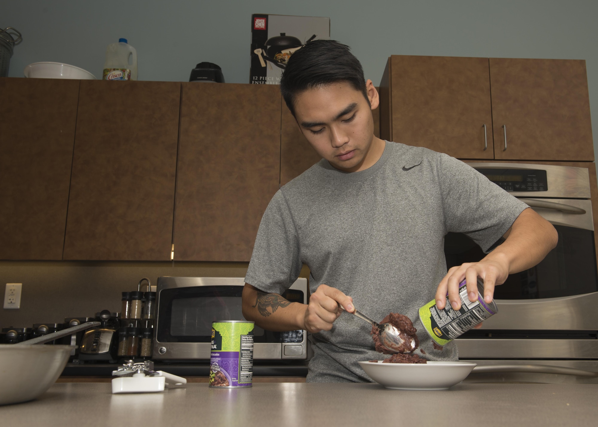 Senior Airman Anfernee Christian Buenaventura, 436th Maintenance Squadron, scoops black beans out of can during a Dorm to Gourm class Oct. 11, 2016, inside the fitness center on Dover Air Force Base, Del. Buenaventura was one of six students who participated in the class. (U.S. Air Force photo by Senior Airman Zachary Cacicia)