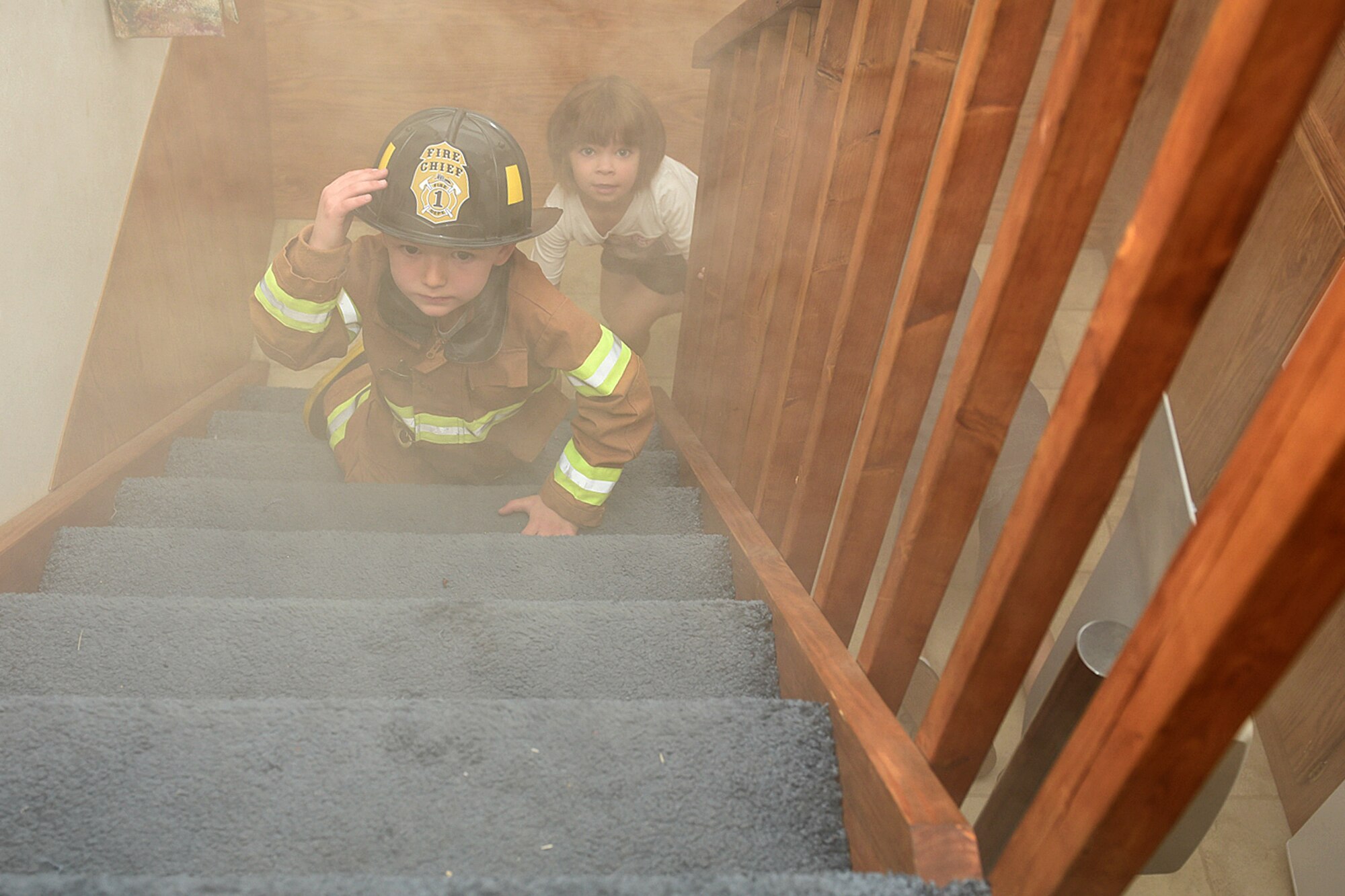 PETERSON AIR FORCE BASE, Colo. – Jaxson Milanese and Ella Wilson feel their way up the stairs in a smoky fire safety house during the open house at the fire station on Peterson Air Force Base, Colo., Oct. 15, 2016. The trainer is used at local schools and the base child development center to help kids learn what to do in the case of a real fire. (U.S. Air Force photo by Senior Airman Rose Gudex) 