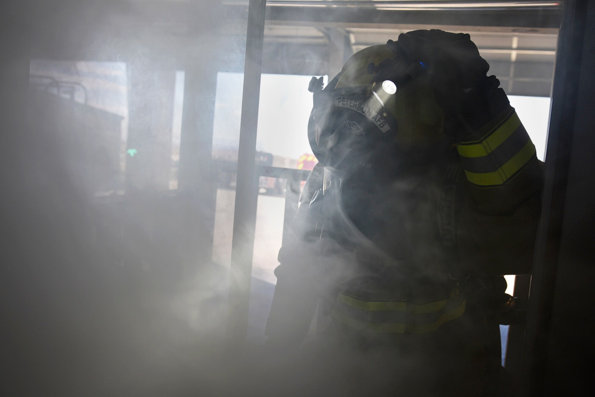 PETERSON AIR FORCE BASE, Colo. –  A Peterson firefighter turns on his headlamp to help a child find their way through the smoke of the fire safety house at the fire station on Peterson Air Force Base, Colo., Oct. 15, 2016. The trainer is used at local schools and the base child development center to help kids learn what to do in the case of a real fire. (U.S. Air Force photo by Senior Airman Rose Gudex) 