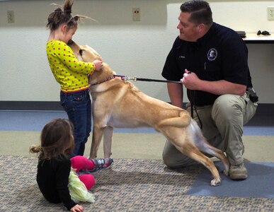 Penny Kruzel, 6, and sister Izzy, 4, greet Gleeson Odin, an electronic-storage-device detection dog with the Anchorage Police Department, at the Joint Base Elmendorf-Richardson library, Oct. 15, 2016. Up to three working dogs can be at any given Paws to Read session and can sit with up to 15 children in 20 minute intervals. Library staff hope to one day be able to host five dogs, allowing for more children to participate.
