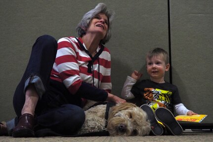 Leland Erker, 2, reads to Sheila Barrett, a therapy dog handler, and Swivel Shot, a therapy dog with Midnight Sun Service Dogs, at the Paws to Read one-year celebration at the Joint Base Elmendorf-Richardson library, Oct. 15, 2016. Up to three working dogs can be at any given Paws to Read session and can sit with up to 15 children in 20 minute intervals. 