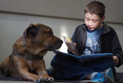 Aiden Patterson, 8, reads to Pagan, a service dog with Midnight Sun Service Dogs, at the Paws to Read one-year celebration at the Joint Base Elmendorf-Richardson library, Oct. 15, 2016. Library staff hope to one day be able to host five dogs, allowing for more children to participate.