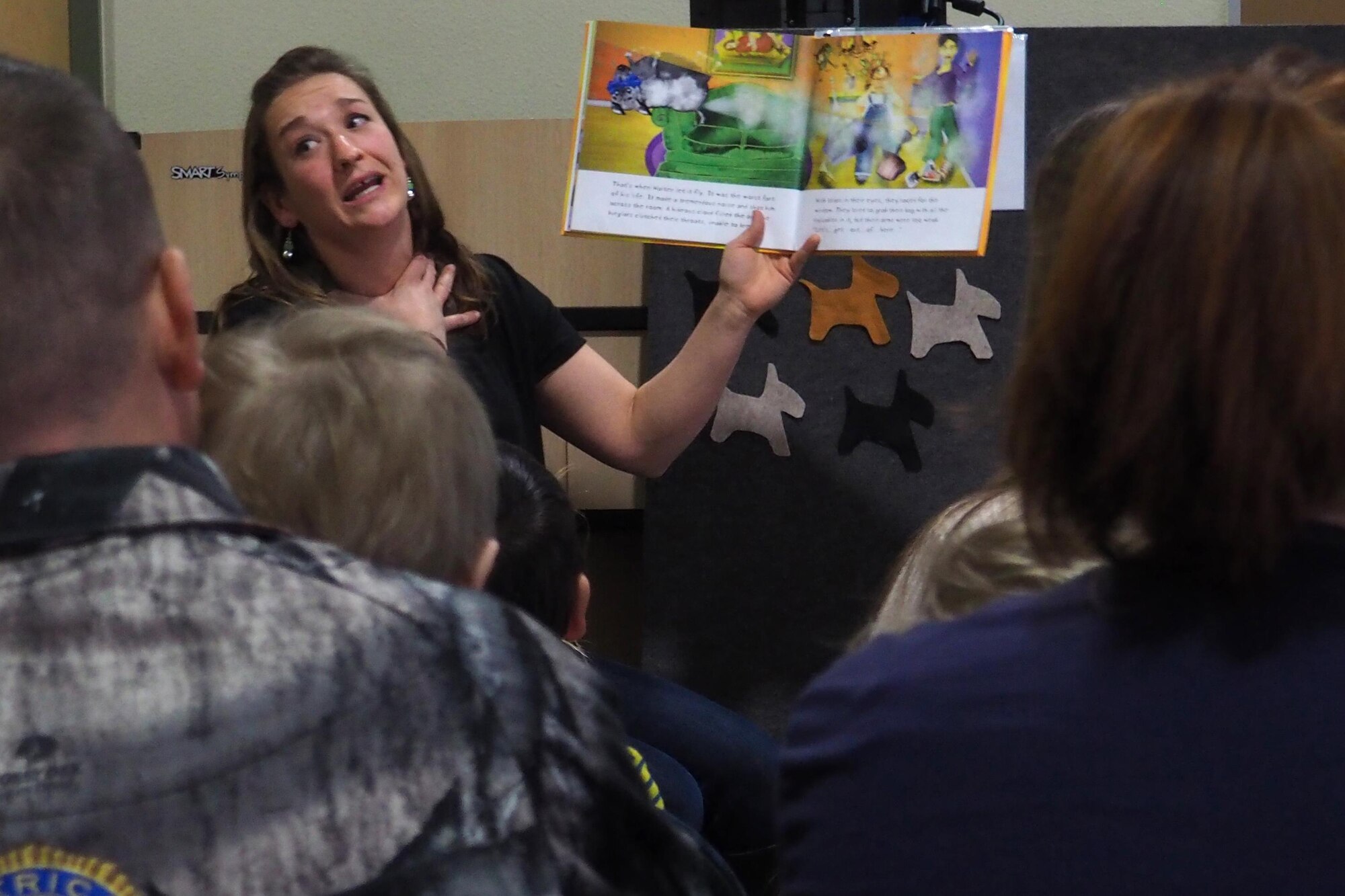 Abbey Kruzel, a story time artist, reads to parents and children at the Paws to Read one year celebration at the Joint Base Elmendorf-Richardson library, Oct. 15, 2016. Up to three working dogs can be at any given Paws to Read session and can sit with up to 15 children in 20 minute intervals.