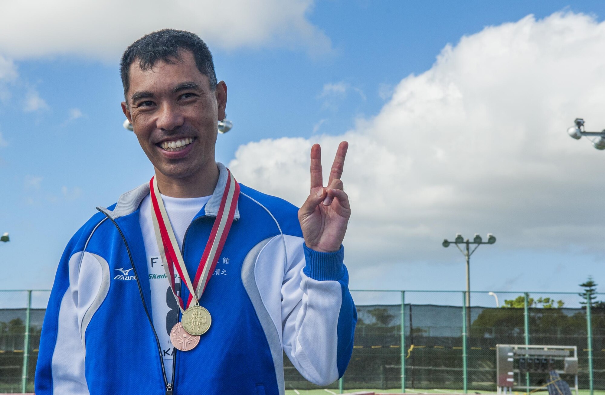Kadena Special Olympics athlete Yoshie Nakamura smiles and give a peace sign after receiving a first place medal for his heat in the standing long jump during the Kadena Special Olympics Nov. 7, 2015, at Kadena Air Base, Japan. This year marks the 16th anniversary of KSO, a sporting event dedicated to enriching the lives of American and Okinawan special needs individuals. (U.S. Air Force photo by Airman 1st Class Nicholas Emerick)