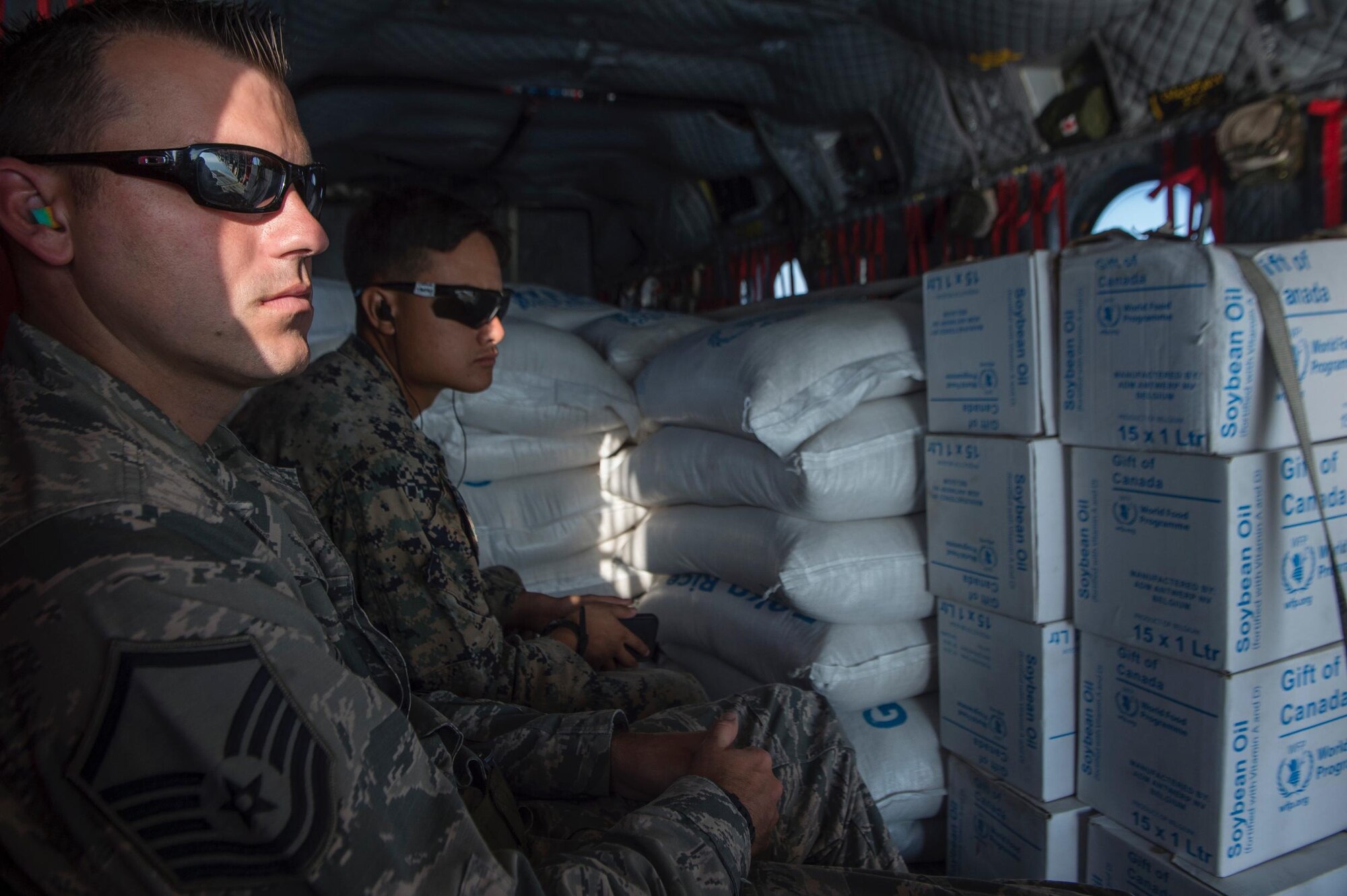 U.S. Air Force Master Sgt. Gabriel Peterson, with the 290th Joint Communications Support Element, and U.S. Marine Corps. Cpl. Phillip Truong, with the Special Purpose Marine Air-Ground Task Force - Southern Command, fly with rice and cooking oil to Beaumont, Haiti, Oct. 13, 2016. The service members are part of Joint Task Force Matthew, which has delivered more than 440 tons of supplies to Haitians affected by Hurricane Matthew. (U.S. Air Force Photo by Tech. Sgt. Russ Scalf)