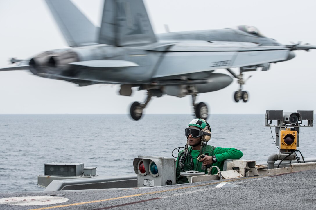 Navy Seaman Eyob Adera performs a safety watch as an F/A-18E Super Hornet launches from the flight deck of the USS Ronald Reagan during Invincible Spirit, an exercise off the southern coast of South Korea, Oct. 13, 2016. The aircraft is assigned to Strike Fighter Squadron 115. Navy photo by Petty Officer 3rd Class Nathan Burke 