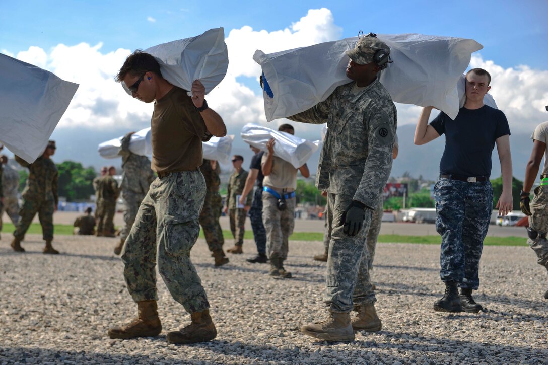 Service members attached to Joint Task Force Matthew load supplies onto a CH-53E Super Stallion helicopter assigned to Marine Medium Tiltrotor Squadron 365 for delivery in Port-au-Prince, Haiti, Oct. 17, 2016. JTF Matthew is providing humanitarian aid and disaster relief to Haiti following Hurricane Matthew. Navy photo by Petty Officer 2nd Class Andrew Murray