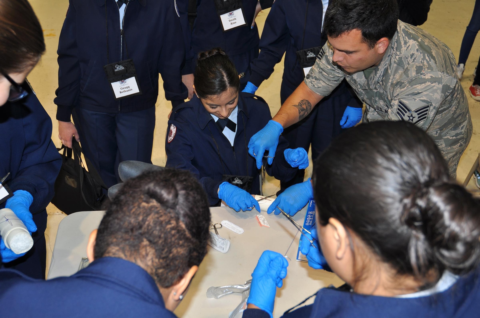 Staff Sgt. Christopher Bock-Bacalao, 445th Aerospace Medicine Squadron, shows how to perform a suture using gauze to simulate a patient during a demonstration by AMDS for students attending the Wings of Women Conference held at the 445th Airlift Wing Sept. 30, 2016. (U.S. Air Force photo/Staff Sgt. Rachel Ingram)