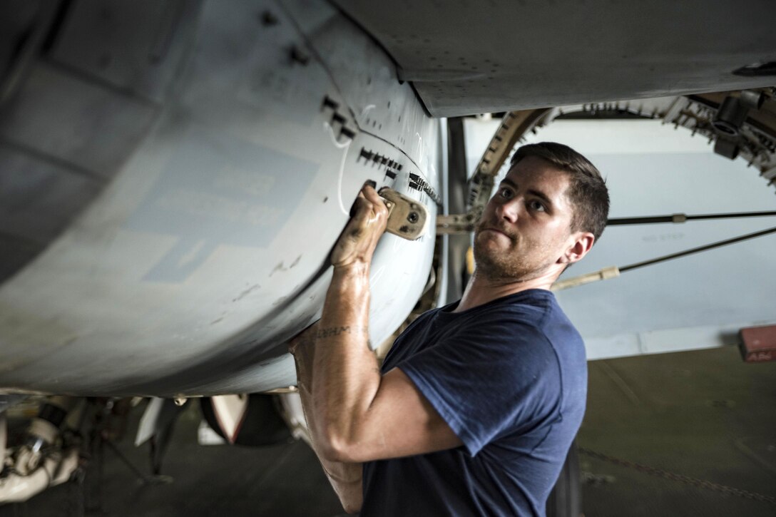 Navy Petty Officer 2nd Class Andrew Moore opens the engine bay of an F/A-18E Super Hornet aircraft in the hangar bay of the aircraft carrier USS Dwight D. Eisenhower in the Persian Gulf, Oct. 16, 2016. Moore is an aviation machinist's mate. Navy photo by Seaman Christopher A. Michaels