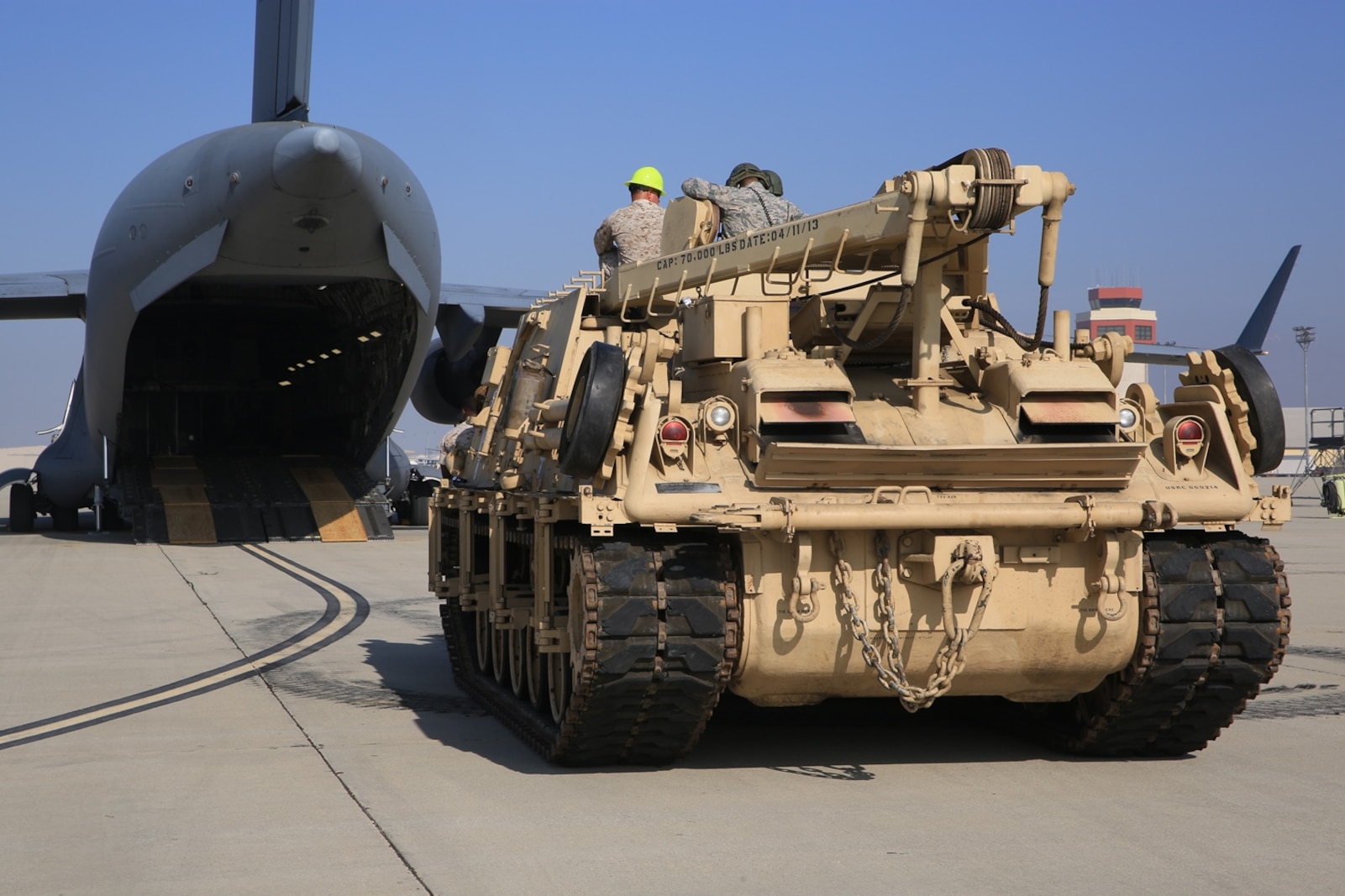U.S. Marines and Airmen wait on a M-88A2 HERCULES for the C-17 Globemaster III’s aircrew to guide them aboard the aircraft at March Air Force Reserves Base, Calif., Oct. 14, 2016. The C-17’s loadmasters are checking that the plywood shoring is properly placed to ensure the aircraft will not be damaged in the loading process.