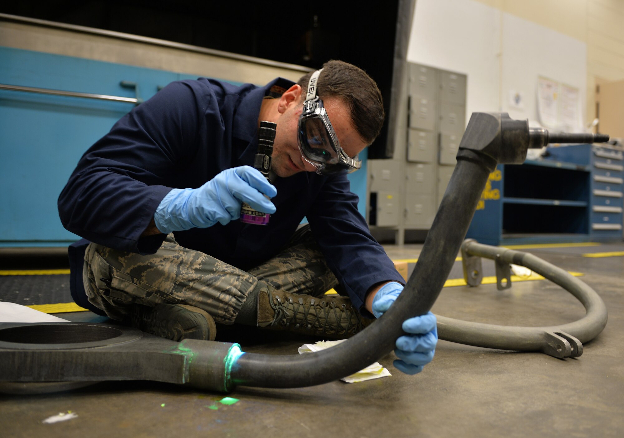 Airman 1st Class Brian Sheldon, a non-destructive inspection journeyman with the 1st Special Operations Maintenance Squadron, stands with a magnetic particle unit at Hurlburt Field Fla., Oct. 17, 2016. A magnetic particle unit blocks light from hitting the prop rod allowing the florescent light to glow indicating imperfections on parts. These specialist use noninvasive methods to inspect the insides of metal objects to identify possible defects in systems and equipment. (U.S. Air Force photo by Senior Airman Andrea Posey)