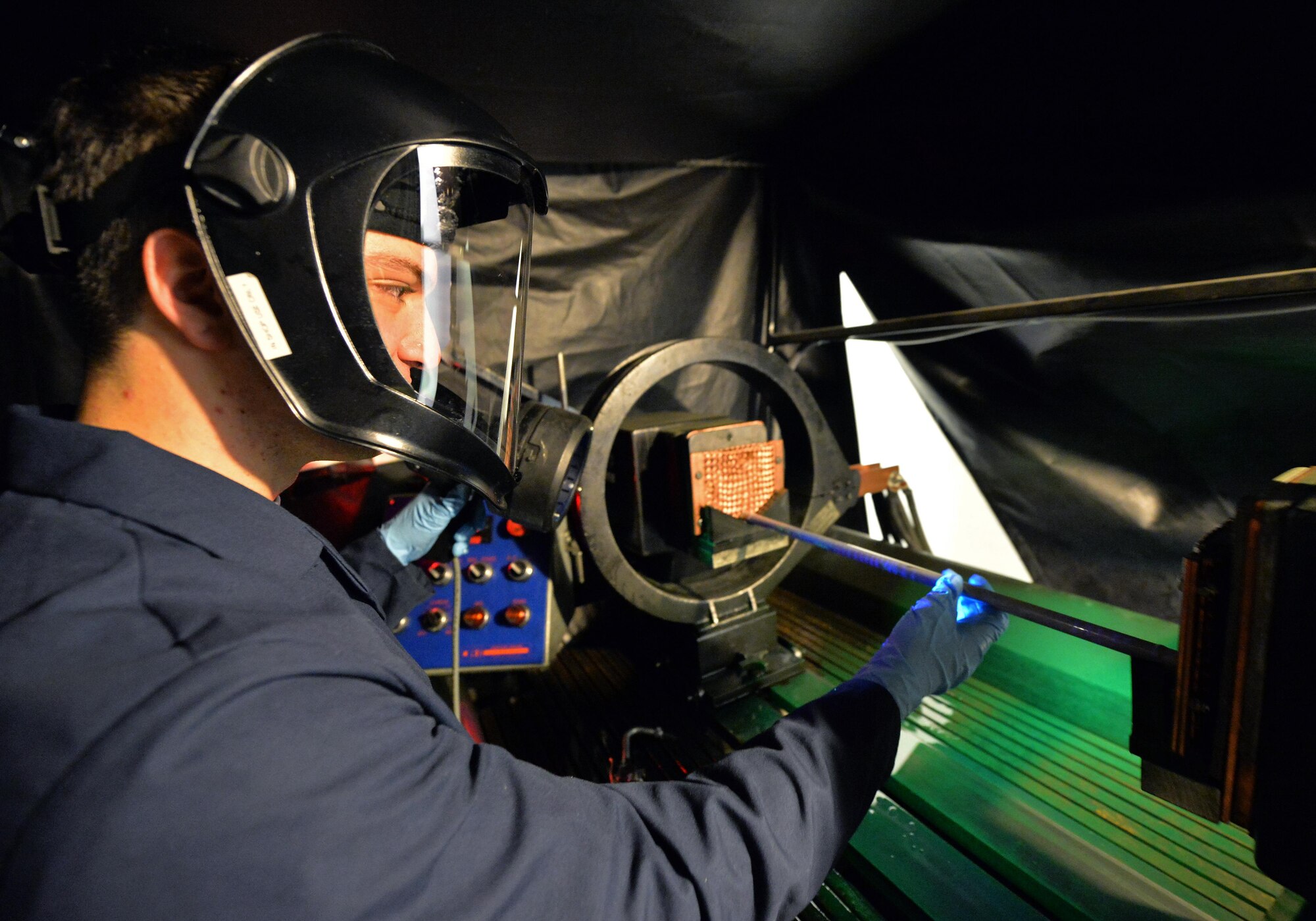 Airman 1st Class Brian Sheldon, a non-destructive inspection journeyman with the 1st Special Operations Maintenance Squadron, stands with a magnetic particle unit at Hurlburt Field Fla., Oct. 17, 2016. A magnetic particle unit blocks light from hitting the prop rod allowing the florescent light to glow indicating imperfections on parts. These specialist use noninvasive methods to inspect the insides of metal objects to identify possible defects in systems and equipment. (U.S. Air Force photo by Senior Airman Andrea Posey)
