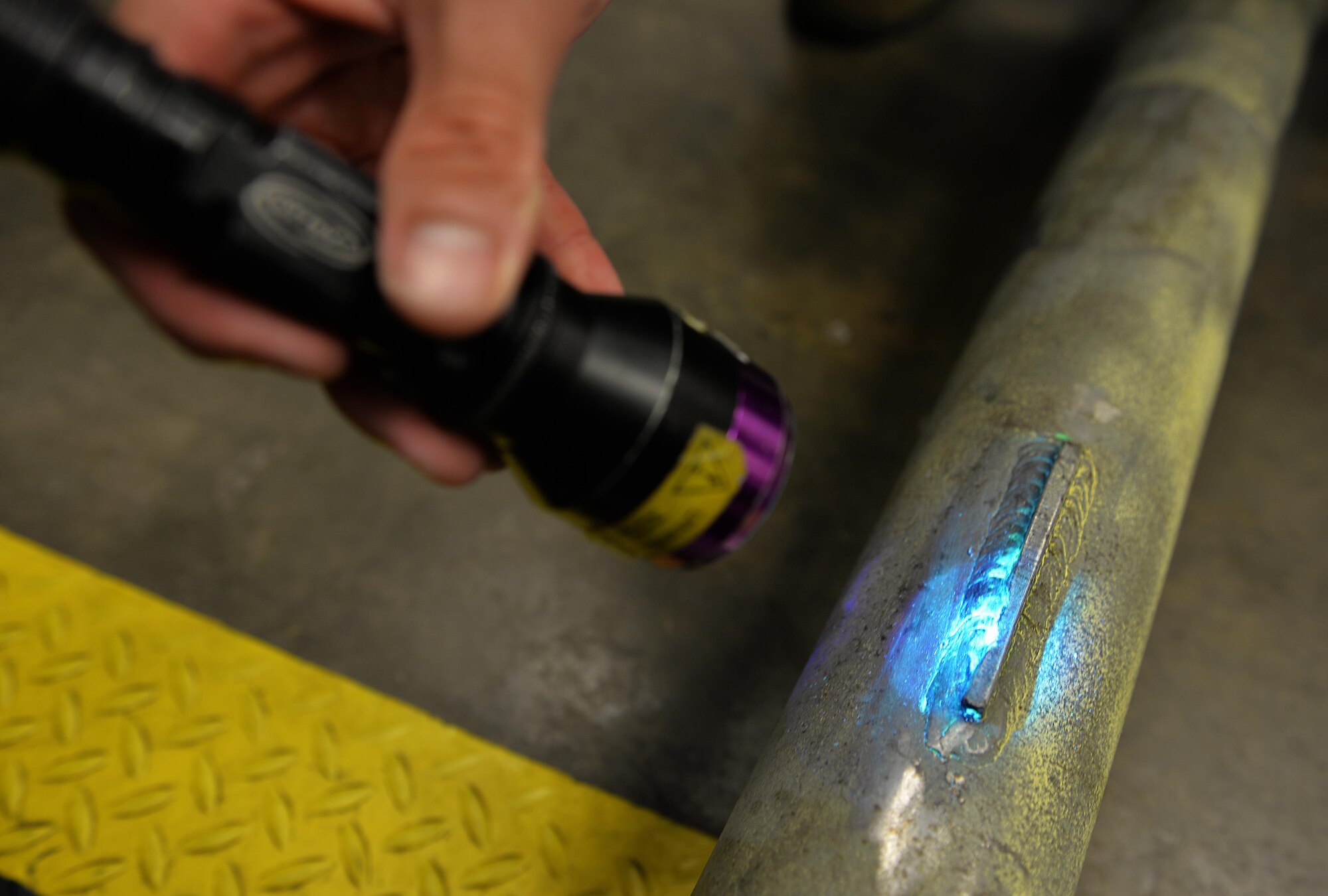 Airman 1st Class Brian Sheldon, a non-destructive inspection journeyman with the 1st Special Operations Maintenance Squadron, stands with a magnetic particle unit at Hurlburt Field Fla., Oct. 17, 2016. A magnetic particle unit blocks light from hitting the prop rod allowing the florescent light to glow indicating imperfections on parts. These specialist use noninvasive methods to inspect the insides of metal objects to identify possible defects in systems and equipment. (U.S. Air Force photo by Senior Airman Andrea Posey)