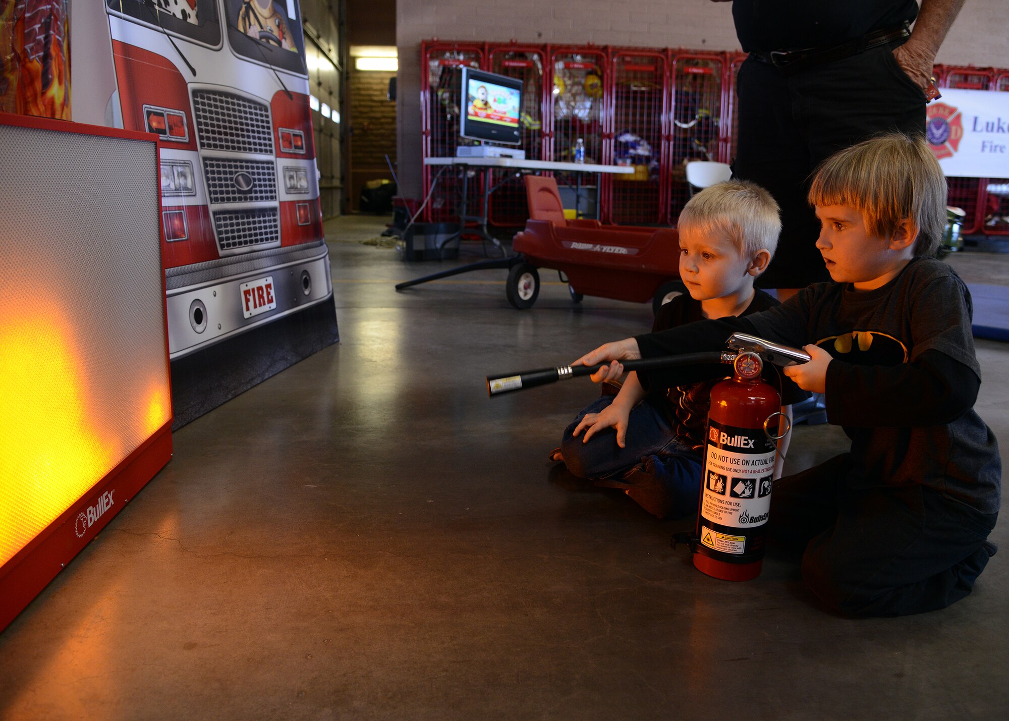 Children use a miniature fire extinguisher to extinguish a simulated fire during the 56th Civil Engineer Squadron fire department open house Oct. 15, 2016 at Luke Air Force Base, Ariz. The fire station open house was available to the public and featured free food, displays, demonstrations and games for children. (U.S. Air Force photo by Senior Airman Devante Williams)