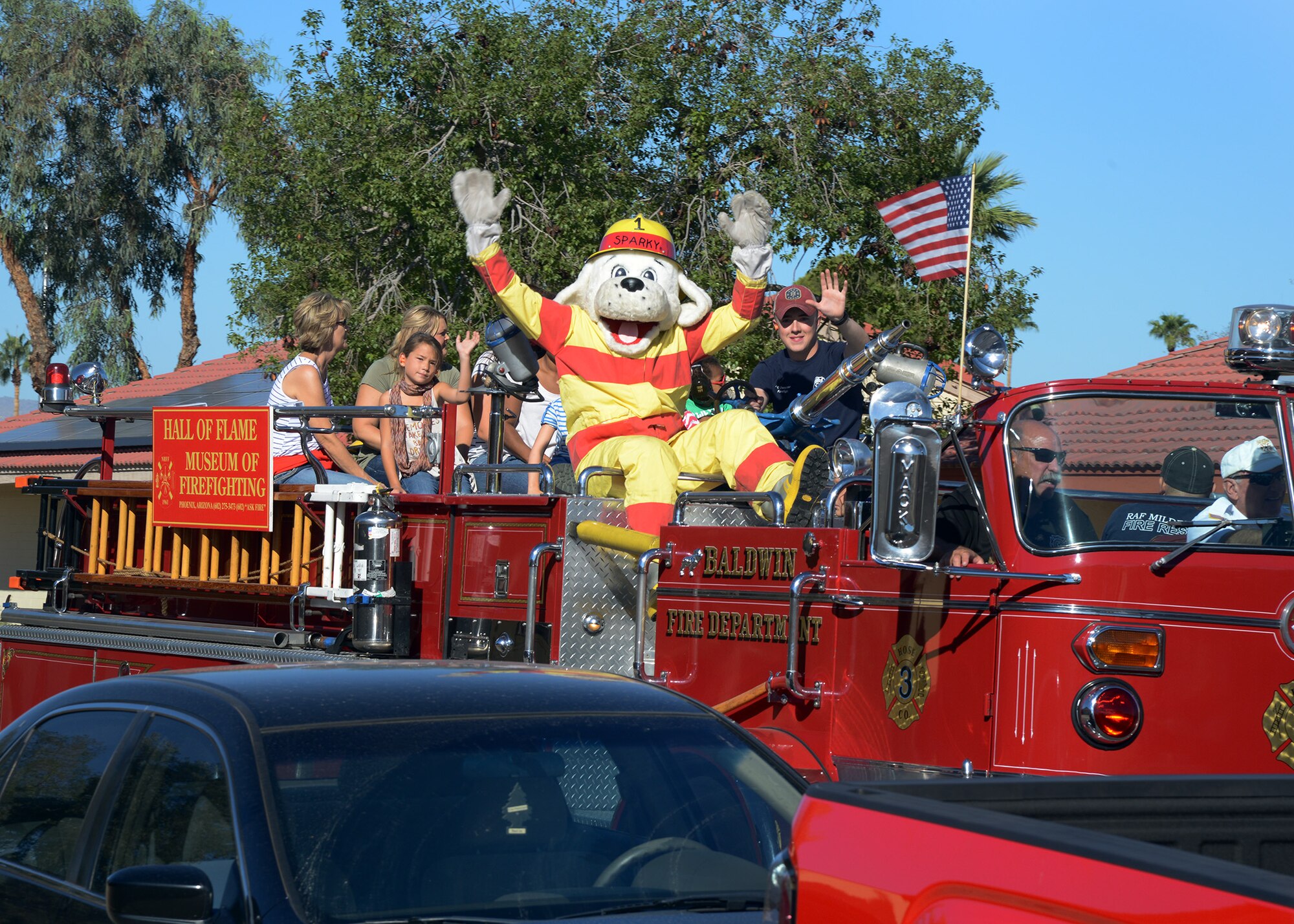 Sparky, the fire dog, waves to base housing residents during the National Fire Prevention Week parade Oct. 15, 2016 at Luke Air Force Base, Ariz. The parade consisted of members and vehicles from Luke’s fire department and the Hall of Flame Fire Museum. (U.S. Air Force photo by Senior Airman Devante Williams)