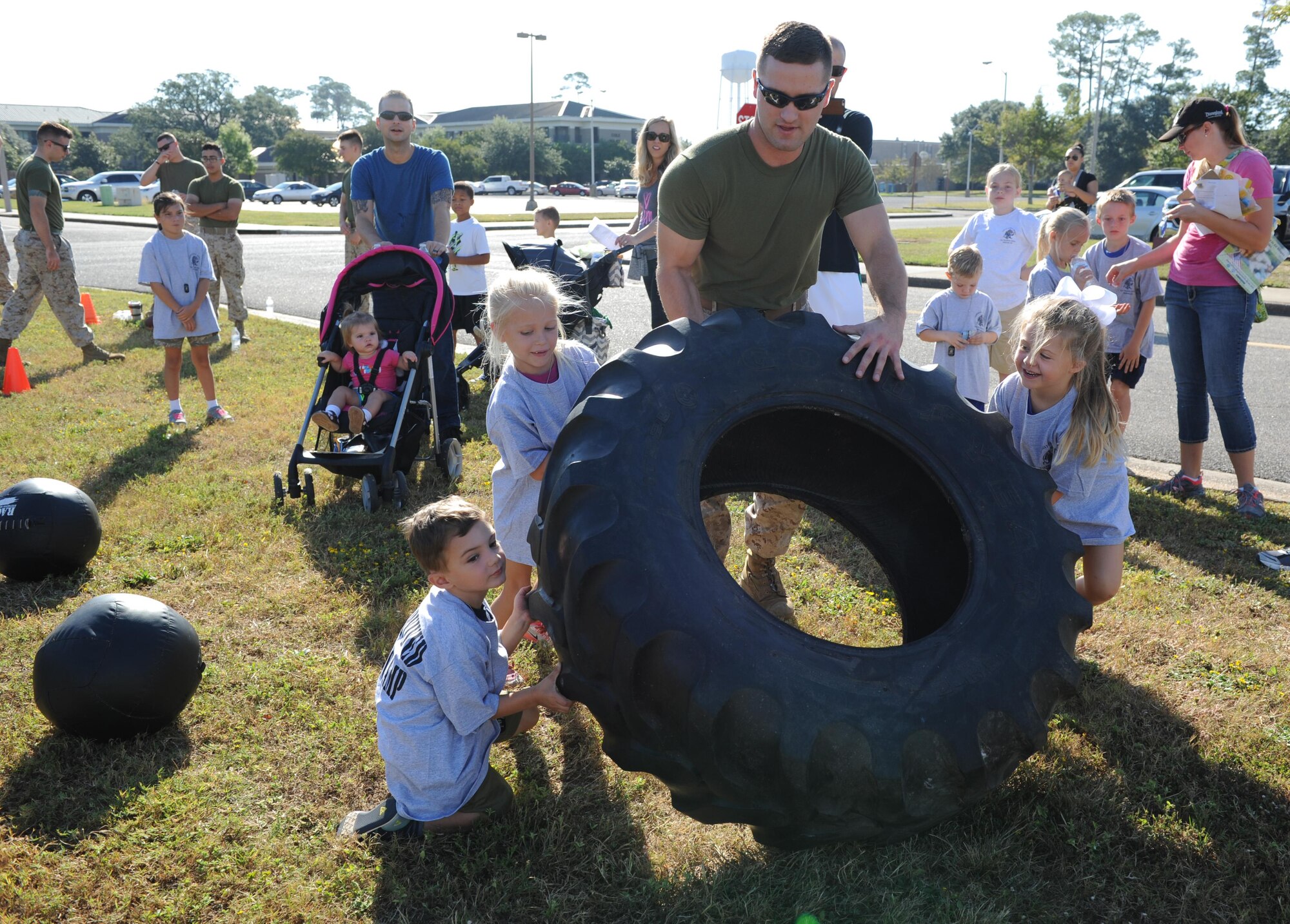 U.S. Marine Sgt. Paul Tutor, Keesler Marine Detachment instructor, helps Keesler children flip a tire during Operation Hero Oct. 15, 2016, on Keesler Air Force Base, Miss. The event was designed to help children better understand what their parents do when they deploy. (U.S. Air Force photo by Kemberly Groue/Released)