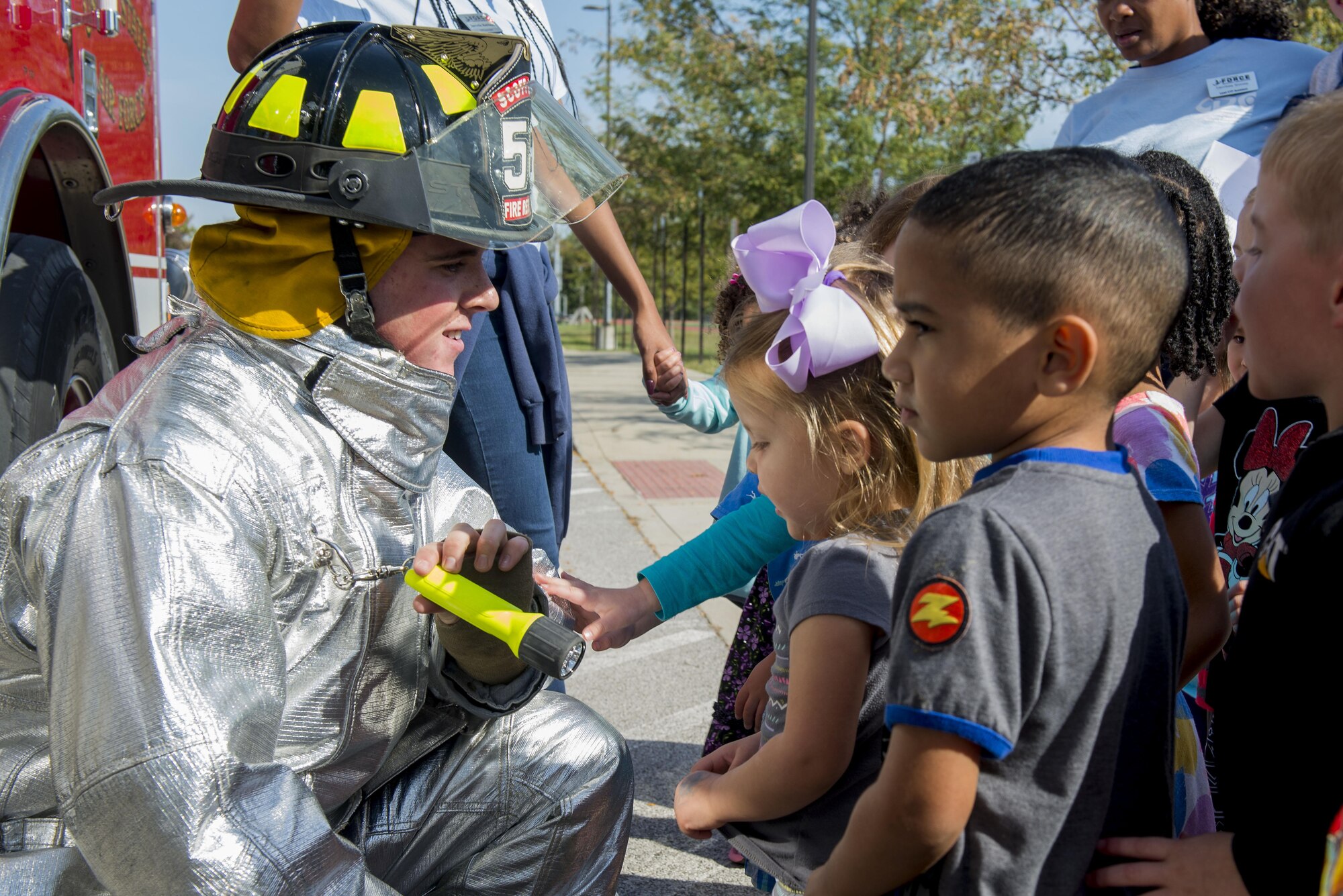 Airman Patrick McLoughlin, 375th Civil Engineering Squadron firefighter, shows a fire suit to children to familiarize kids with the appearance of firefighters during fire prevention week, October 11, 2016 at the Child Development Center. This year’s Fire Prevention Week campaign, “Don’t Wait – Check the Date! Replace Smoke Alarms Every 10 Years,” represents the final year of our three-year effort to educate the public about basic but essential elements of smoke alarm safety. (U.S. Air Force photo by Senior Airman Joshua Eikren)