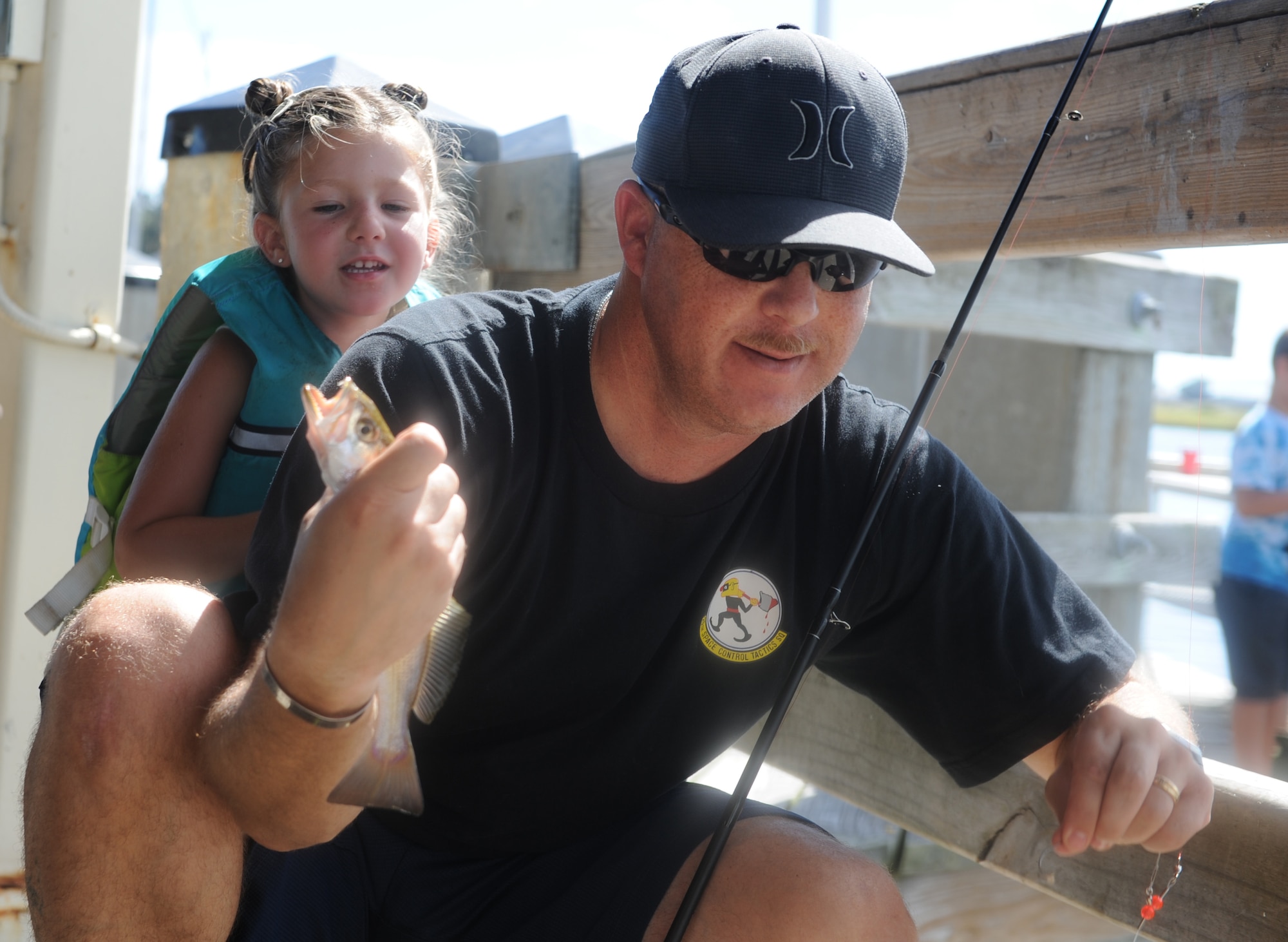 Madilynn Clifford, hides behind her dad, Master Sgt. Joseph Clifford, 81st Training Supports Squadron first sergeant, as he holds up a fish they caught during the Kids’ Fishing Rodeo at the marina Oct. 15, 2016, on Keesler Air Force Base, Miss. Over 90 participants attended the event where prizes were awarded for different categories and free food was available.  (U.S. Air Force photo by Kemberly Groue/Released)