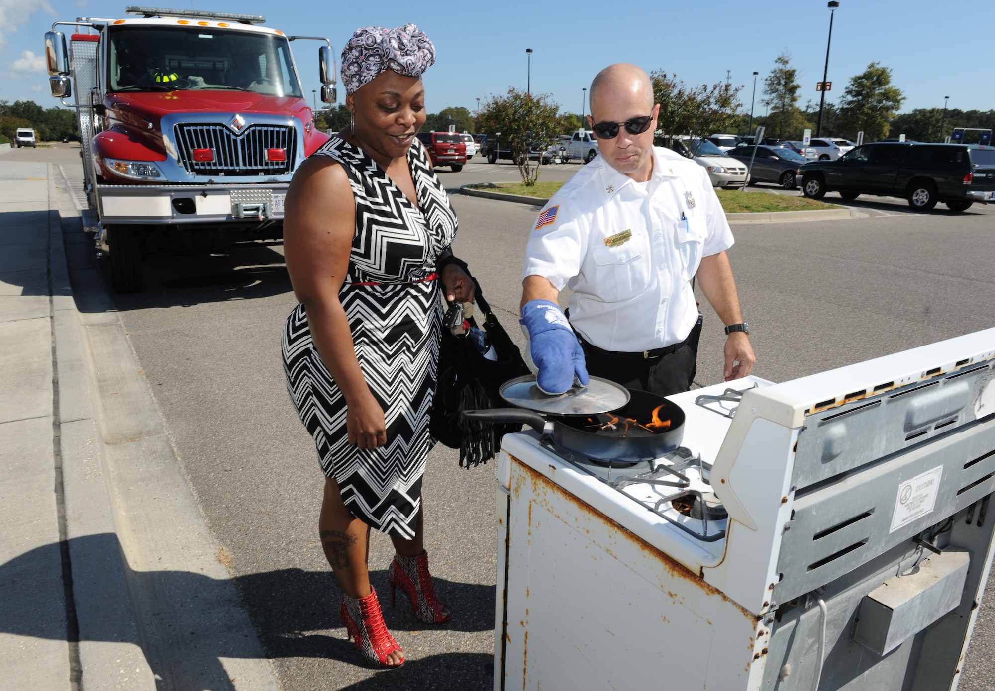 Jason Sanders, 81st Infrastructure Division fire prevention assistant chief, demonstrates how to safely put out a stove fire to Ieasha Sims, Keesler Base Exchange sales associate, during Fire Prevention Week outside of the Base Exchange Oct. 11, 2016, on Keesler Air Force Base, Miss. The week-long event included fire drills, literature hand-outs and stove fire demonstrations around the base and concludes with an open house at the fire department. (U.S. Air Force photo by Kemberly Groue/Released)