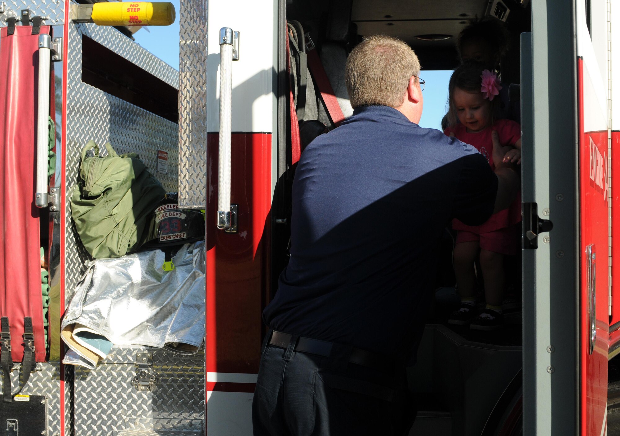 Cole Ballard, 81st Infrastructure Division hazmat technician, helps Abbey Mansfield, daughter of William Mansfield, 81st Logistics Readiness Squadron vehicle maintainer, out of a fire truck during a Fire Prevention Week demonstration at the CDC Oct. 12, 2016, on Keesler Air Force Base, Miss. The week-long event included fire drills, literature hand-outs and stove fire demonstrations around the base and concluded with an open house at the fire department. (U.S. Air Force photo by Senior Airman Holly Mansfield/Released)