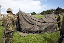 Members of the Japan Ground Self-Defense Force set up tents during the annual Guard and Protect, an observe and exchange event, Oct. 6 on Marine Corps Air Station Futenma, Okinawa, Japan. The event allowed U.S. and JGSDF service members to observe each other’s operation procedures in order to sharpen their defense skill sets and strengthen their bilateral relationship. The observation and exchange included troop movement, escalation of force, and vehicle search and seizure.