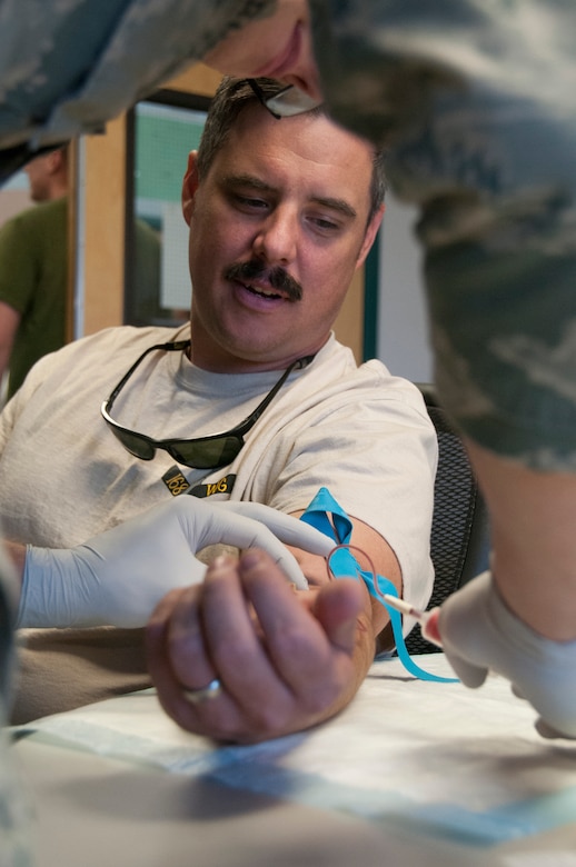 Senior Airman Zach Raby, medical technician with the 168th Medical Group, Alaska Air National Guard, takes a blood sample from Master Sgt. Jeff Skaggs during in-processing procedures at the wing’s operations building October 16, 2016. Thirty-four Airmen from the 168th returned home after an extended deployment to Southwest Asia, and were greeted by family, friends, and co-workers inside the unit’s maintenance hangar here on Eielson AFB. (U.S. Air National Guard photo by Senior Master Sgt. Paul Mann))