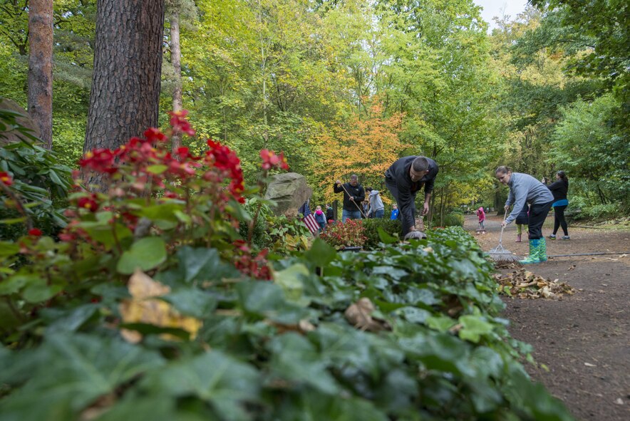 Members of the 86th Operations Support Squadron team rake leaves and clean around bushes at the American Kindergraves in Kaiserslautern, Germany, Oct. 15, 2016. Approximately 30 members volunteered to clean the site. (U.S. Air Force photo by Senior Airman Tryphena Mayhugh)