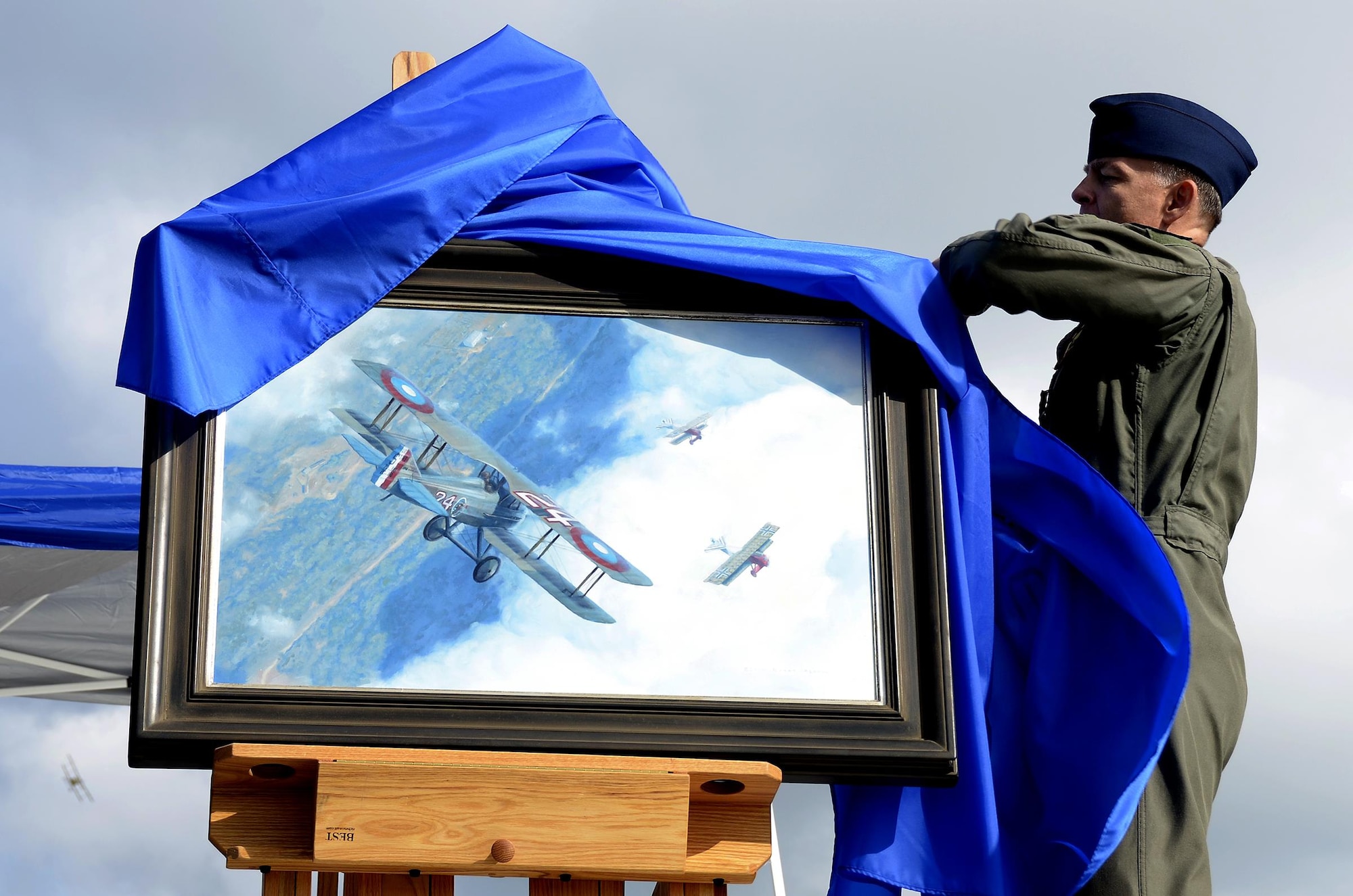 Senior Master Sgt. Darby Perrin, an Air Force artist from the 465th Air Refueling Squadron, Tinker Air Force Base, Oklahoma, unveils his painting at the Dawn Patrol Rendezvous event held at the National Museum of the United States Air Force in Ohio, Oct. 1, 2016. The painting depicts 1st Lt. Charles d’Olive’s victory over three German fighter planes during World War I. (U.S. Air Force photo/Staff Sgt. Joel McCullough)