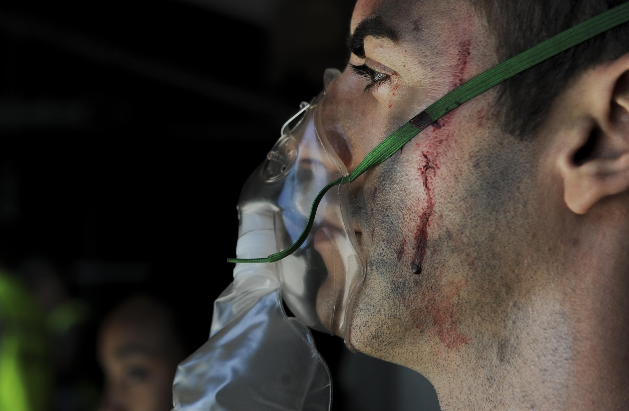 A simulated casualty breaths into a mask in a medical hangar during the Major Accident Recovery Exercise at Nellis Air Force Base, Nev., Oct. 13, 2016. The participants included Wing Inspection Team (WIT) members, Scene Controllers for additional safety, and volunteers simulating victims and witnesses to the incident. (U.S. Air Force photo by Airman 1st Class Kevin Tanenbaum/Released)
