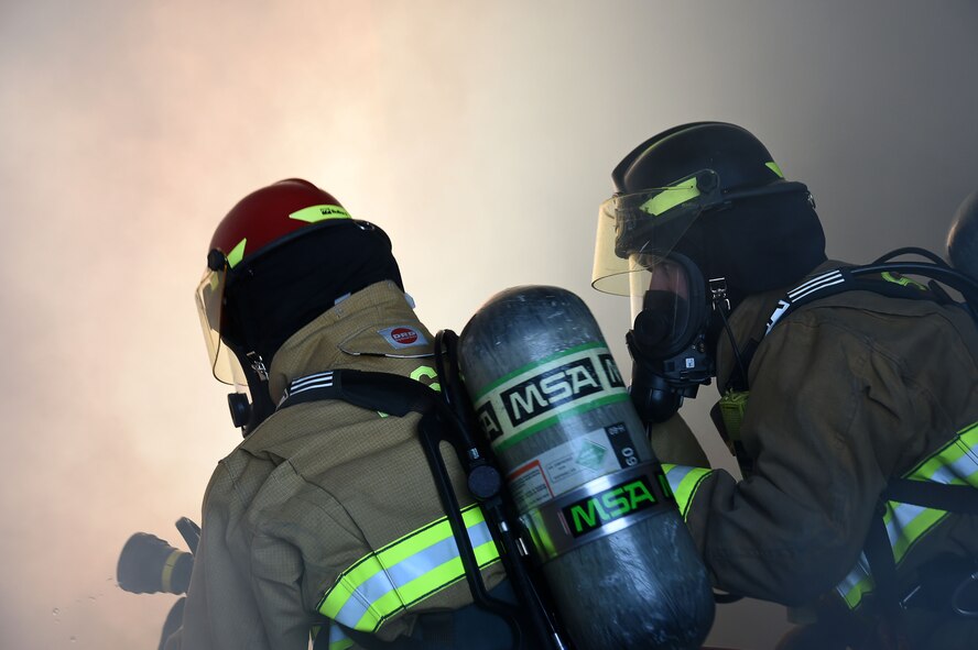 A firefighter assigned to the 99th Civil Engineer Squadron Fire Protection Flight and a distinguished visitor, fight a fire during a live burn training exercise Sept. 23, 2016, at Creech Air Force Base, Nev. The squadron recently won five Air Combat Command awards, four Air Force level awards and two DoD awards for demonstrating a high degree of excellence in fire prevention and protection. (U.S. Air Force photo by Airman 1st Class James Thompson)  