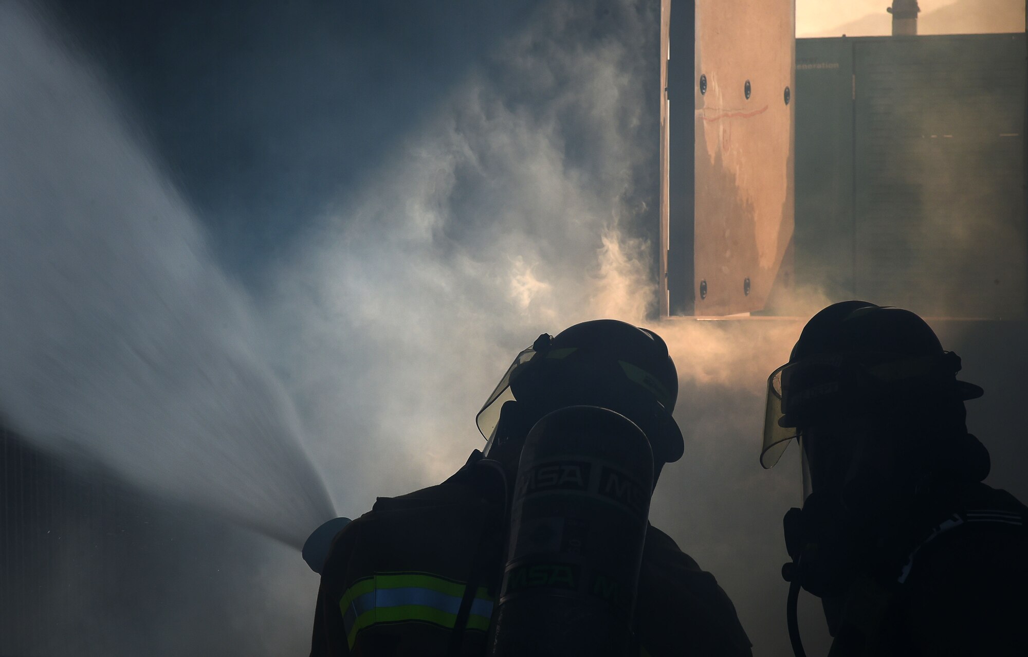 Firefighters assigned to the 99th Civil Engineer Squadron Fire Protection Flight, spray the base of a fire during a live burn training exercise Sept. 23, 2016, at Creech Air Force Base, Nev. The 99th CES Fire and Emergency Services recently won the 2015 DoD Fire Department of the Year and 2015 DoD Fire Prevention Program of the Year awards. (U.S. Air Force photo by Airman 1st Class James Thompson) 