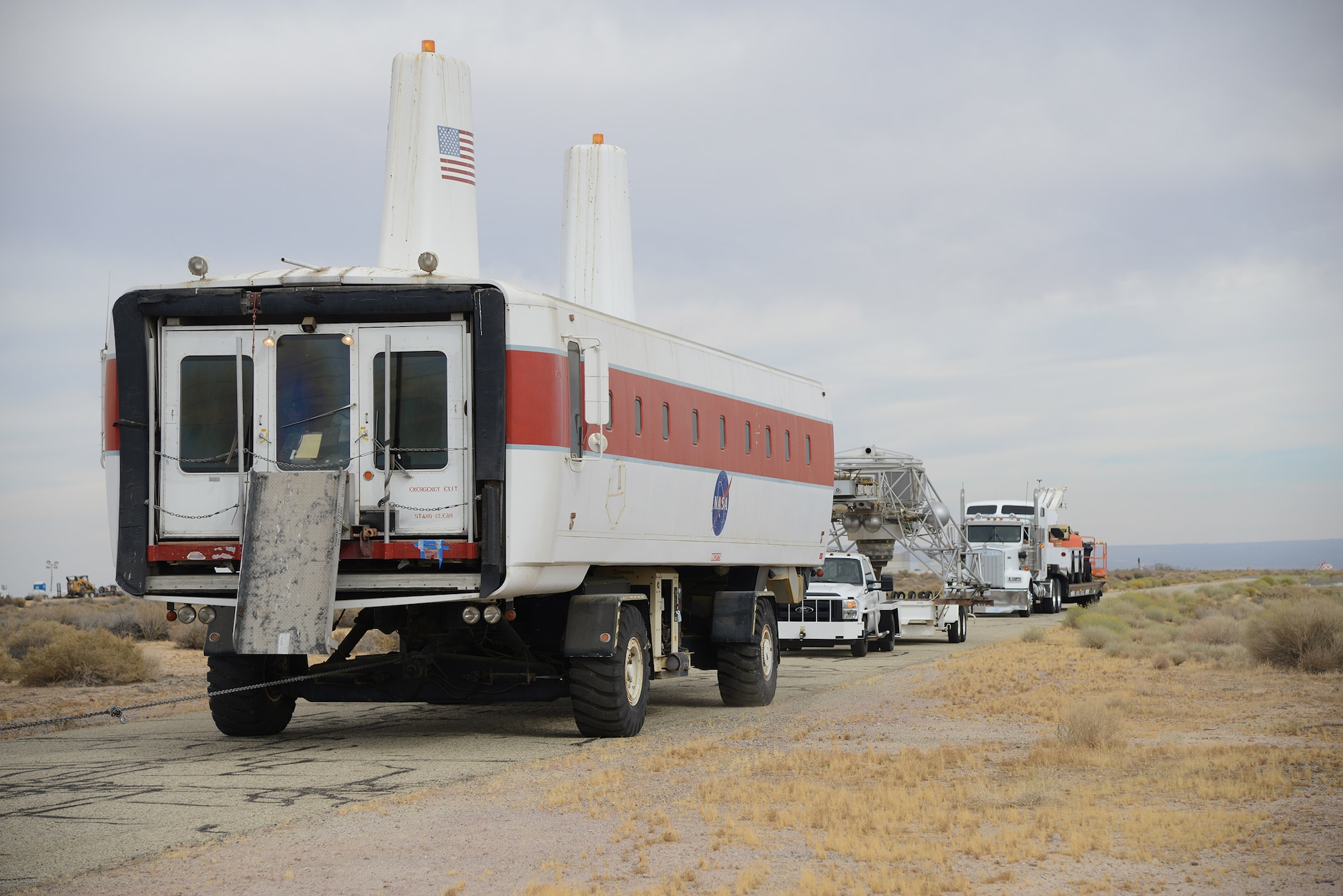 NASA’s Space Shuttle Crew Transport Vehicle and Lunar Landing Research Vehicle pass through the gate at the end of Edwards main runway on their way to the Air Force Flight Test Museum Oct. 13. Both vehicles were donated by NASA’s Armstrong Flight Research Center. (U.S. Air Force photo by Christopher Ball)