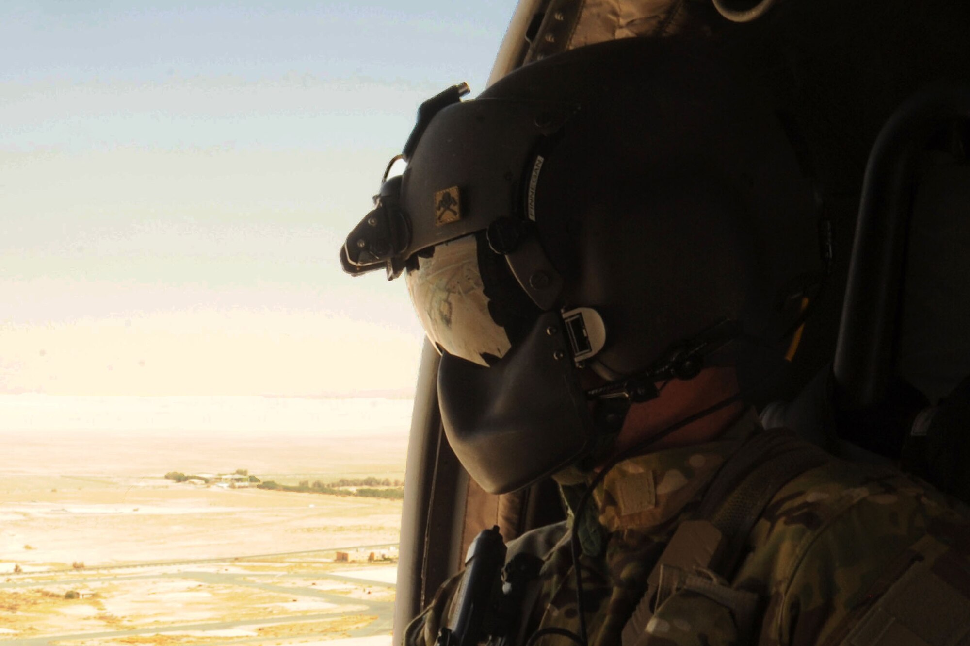 U.S. Army Spc. Shane Finnegan, HH-60G Pave Hawk helicopter crew chief, looks out the side of the aircraft during medical evacuation training Oct. 14, 2016 at an undisclosed location in Southwest Asia. Army flight medics led Air Force first responders and coalition partner medics in med evac training to improve mission capabilities. (U.S. Air Force photo/Senior Airman Zachary Kee)