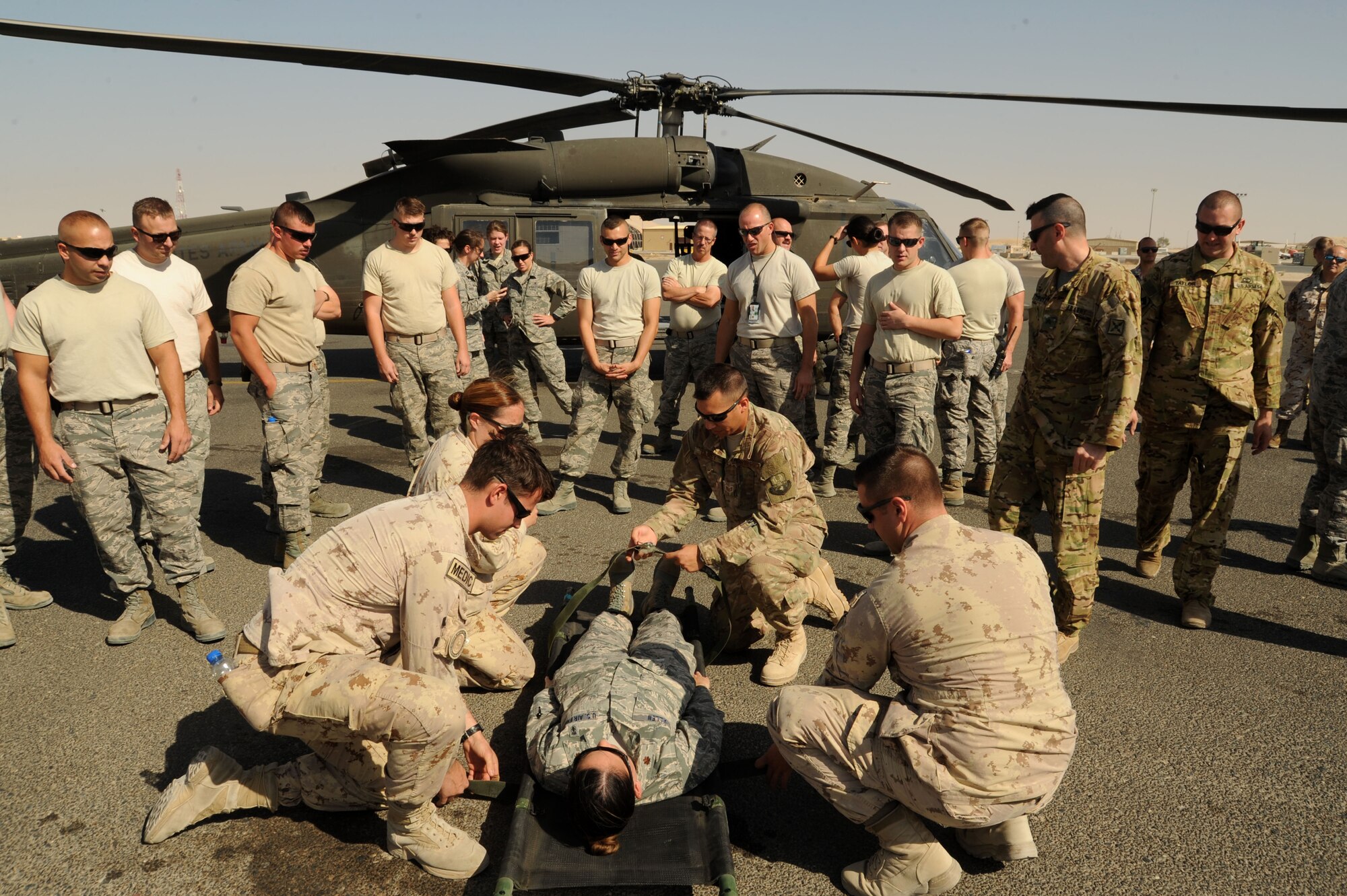 A carry team comprised of Canadian medical personnel and Staff Sgt. Jack Ulrey, 386th Expeditionary Medical Group lab technician, strap down a simulated patient during medical evacuation training Oct. 14, 2016 at an undisclosed location in Southwest Asia. The purpose of the training was to expand mission capabilities and enhance relationships between joint and coalition partners. (U.S. Air Force photo/Senior Airman Zachary Kee)