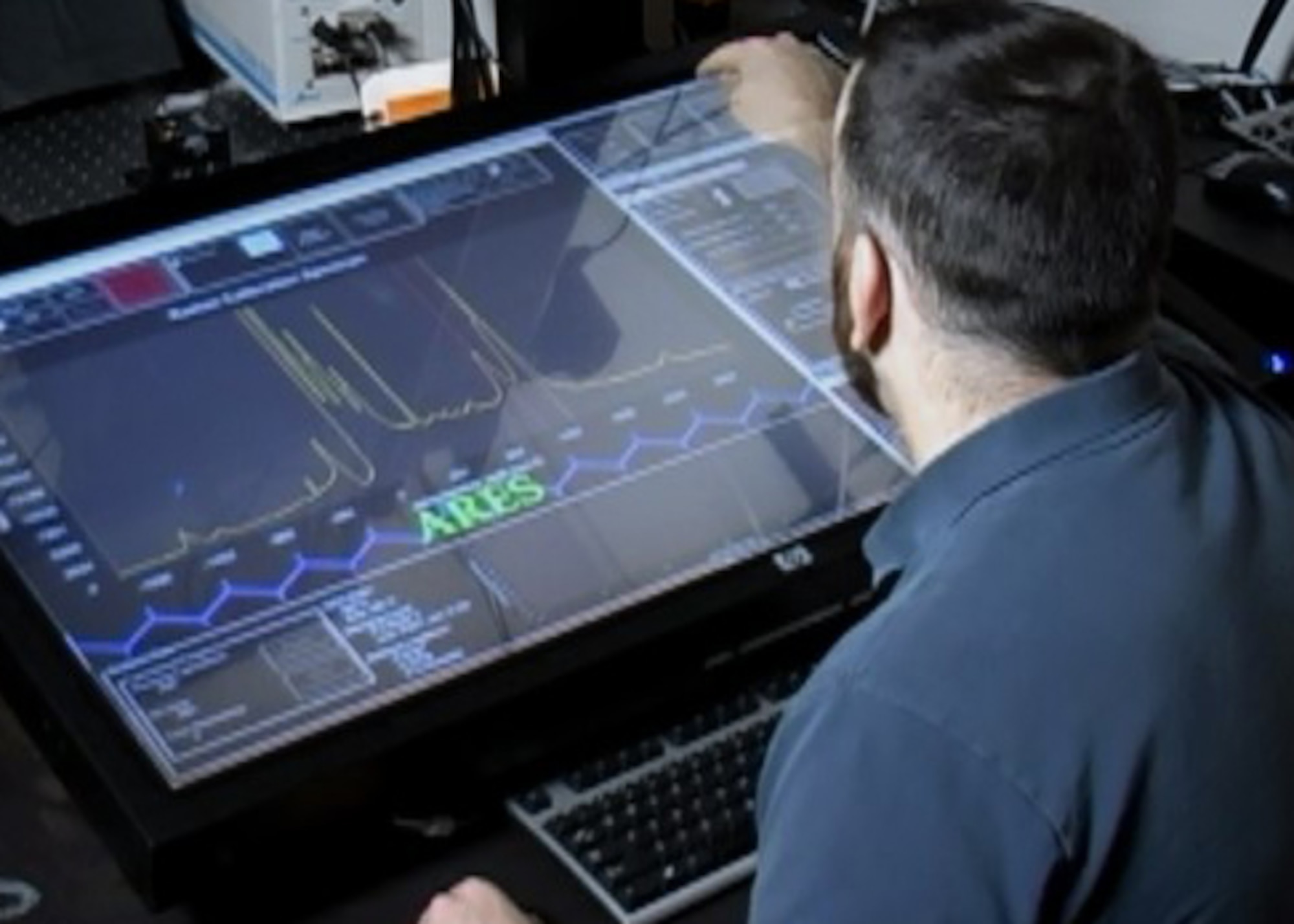A materials researcher examines experimental data on the ARES artificial intelligence planner. The ARES Autonomous Research System, developed by the Air Force Research Laboratory, uses artificial intelligence to design, execute and analyze experiments at a faster pace than traditional scientific research methods. (Courtesy Photo)