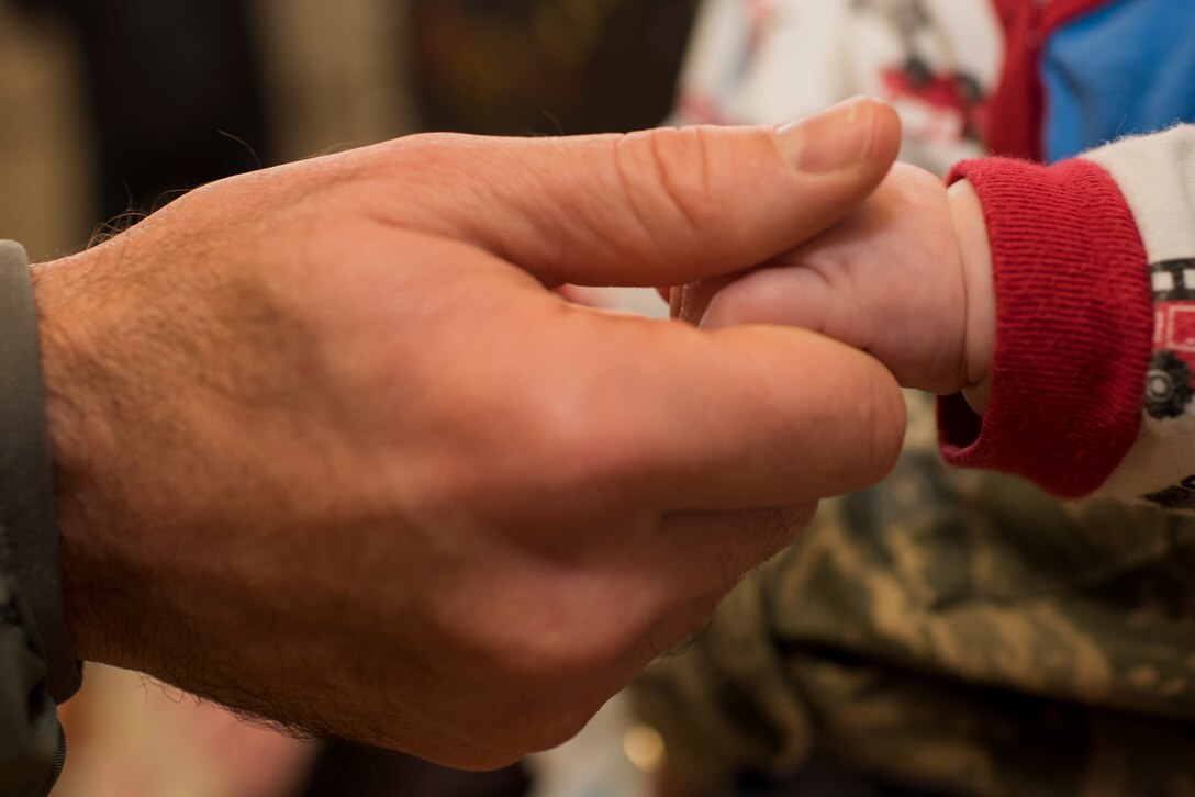 An Airman assigned to the 606th Air Control Squadron holds the hand of an infant child while awaiting the squadron's return from deployment to their squadron at Spangdahlem Air Base, Germany, Oct. 20, 2016. Nearly 200 Airmen assigned to the 606th ACS returned, from a six-month rotational deployment to Southwest Asia in support of Operations Freedom’s Sentinel and Inherent Resolve. (U.S. Air Force photo by Staff Sgt. Joe W. McFadden)