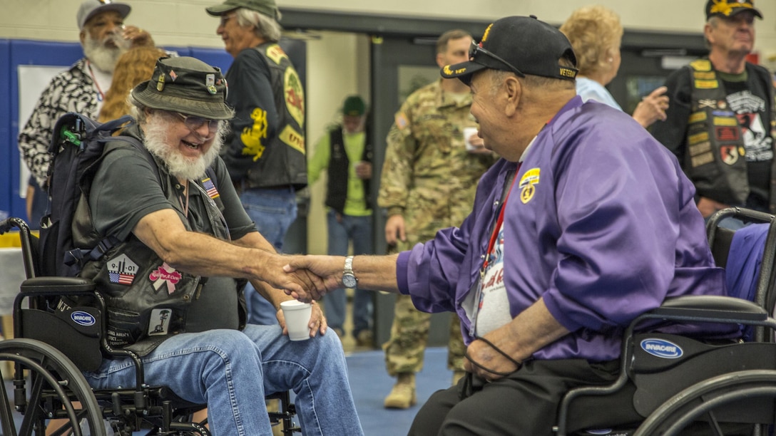 Petty Officer Third Class retired Michael Keenan greets Cpl. retired Jim Caines at the opening breakfast for Honor Flight Savannah aboard U.S. Army Garrison Hunter Army Airfield Fort Stewart, Savannah, GA, Oct. 14. Keenan served as a journalist in the Navy from 1966-1976 and Caines served as an infantryman in the Marine Corps from 1966-1968. Honor Flight Savannah brings together veterans from World War II, Vietnam and Korea for a trip to visit their war memorials at the National Mall in Washington D.C.